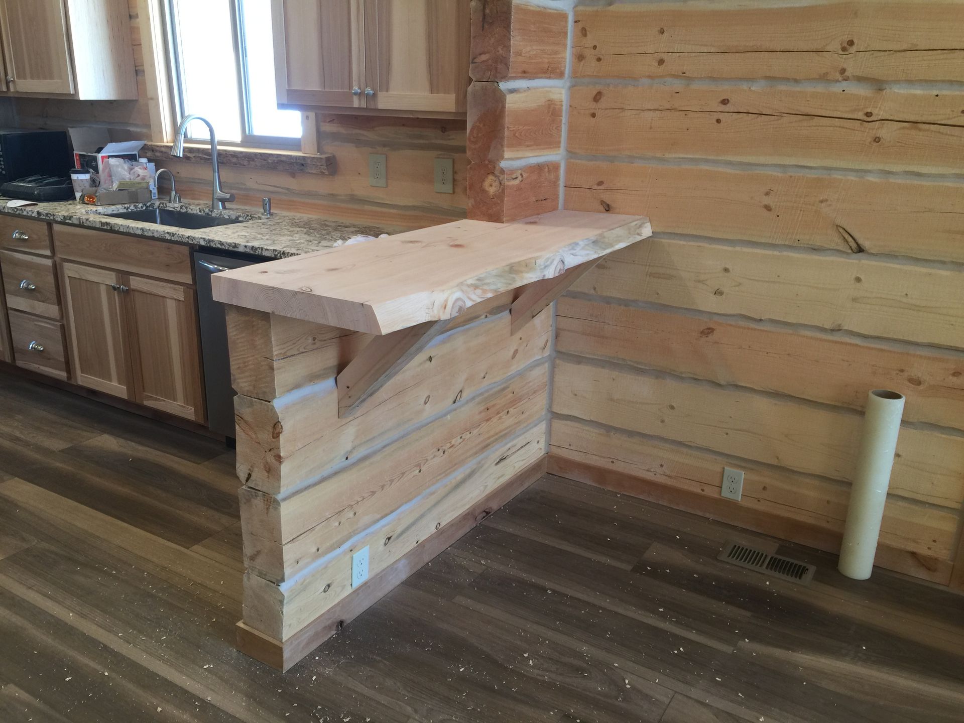A kitchen in a log cabin with a wooden counter top.