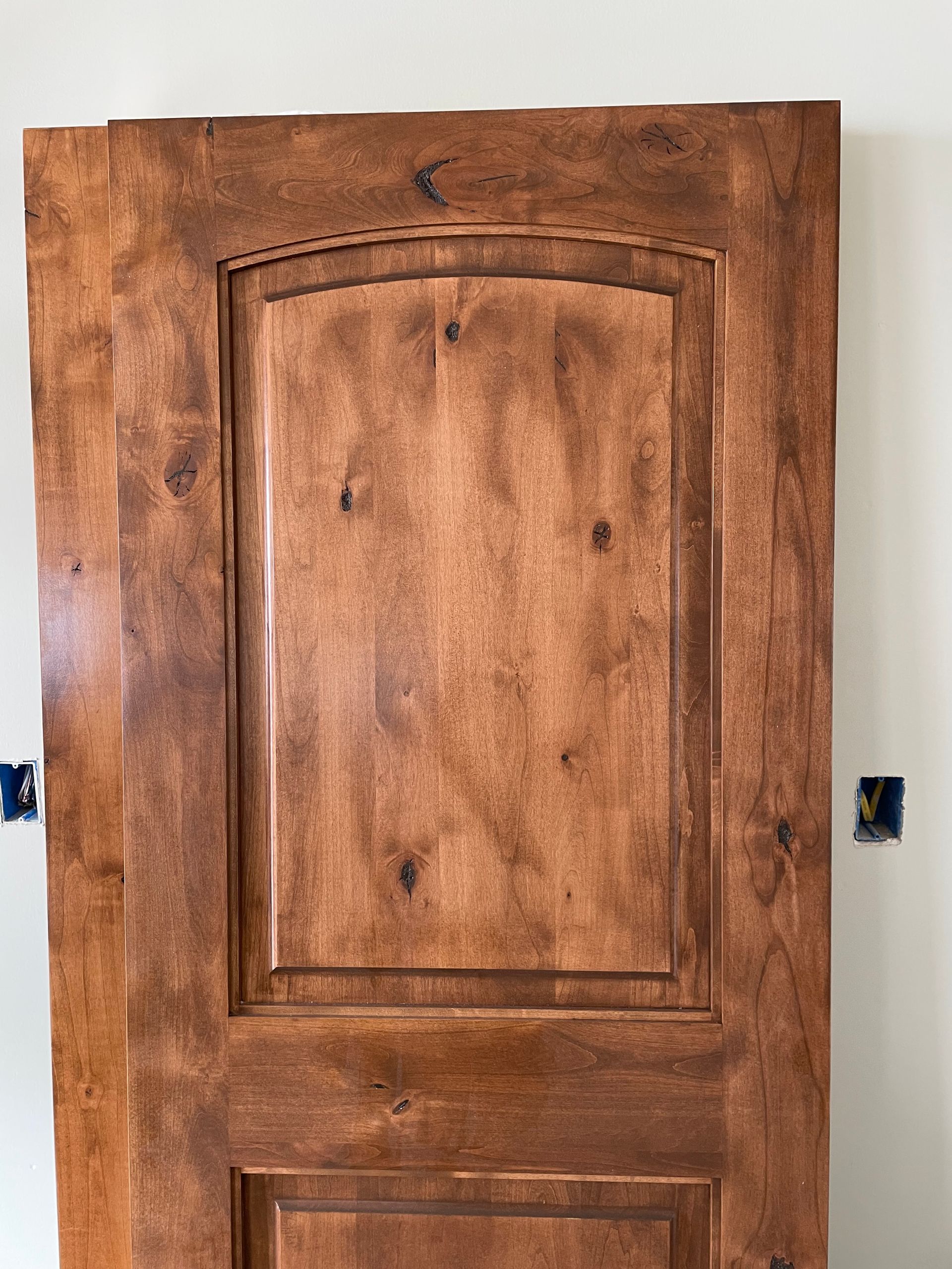 A wooden door is hanging on a white wall.