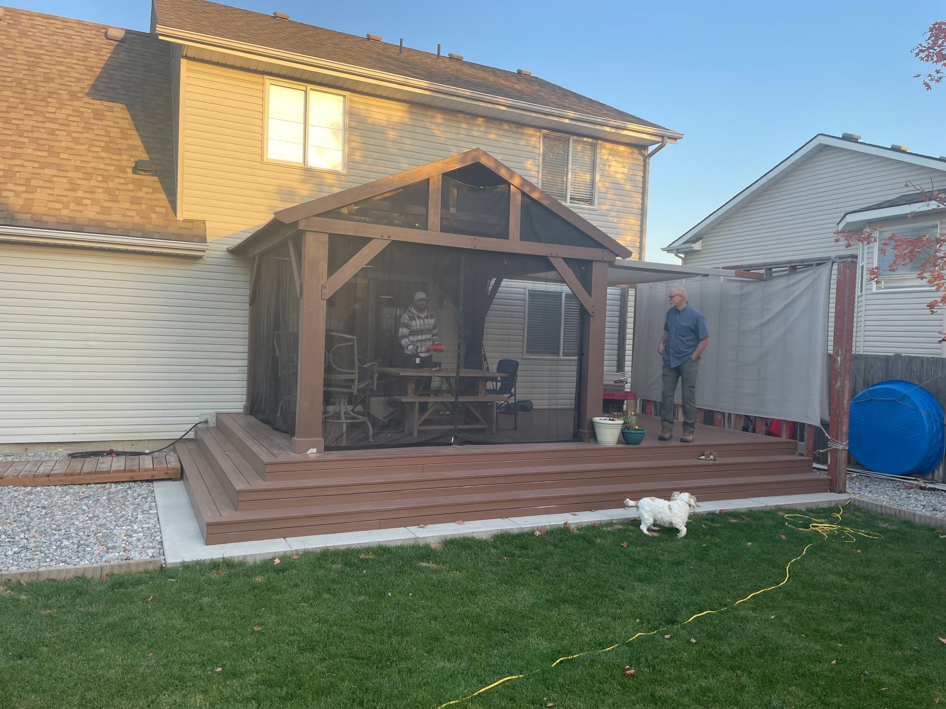 A man and a dog are standing in front of a screened in porch.