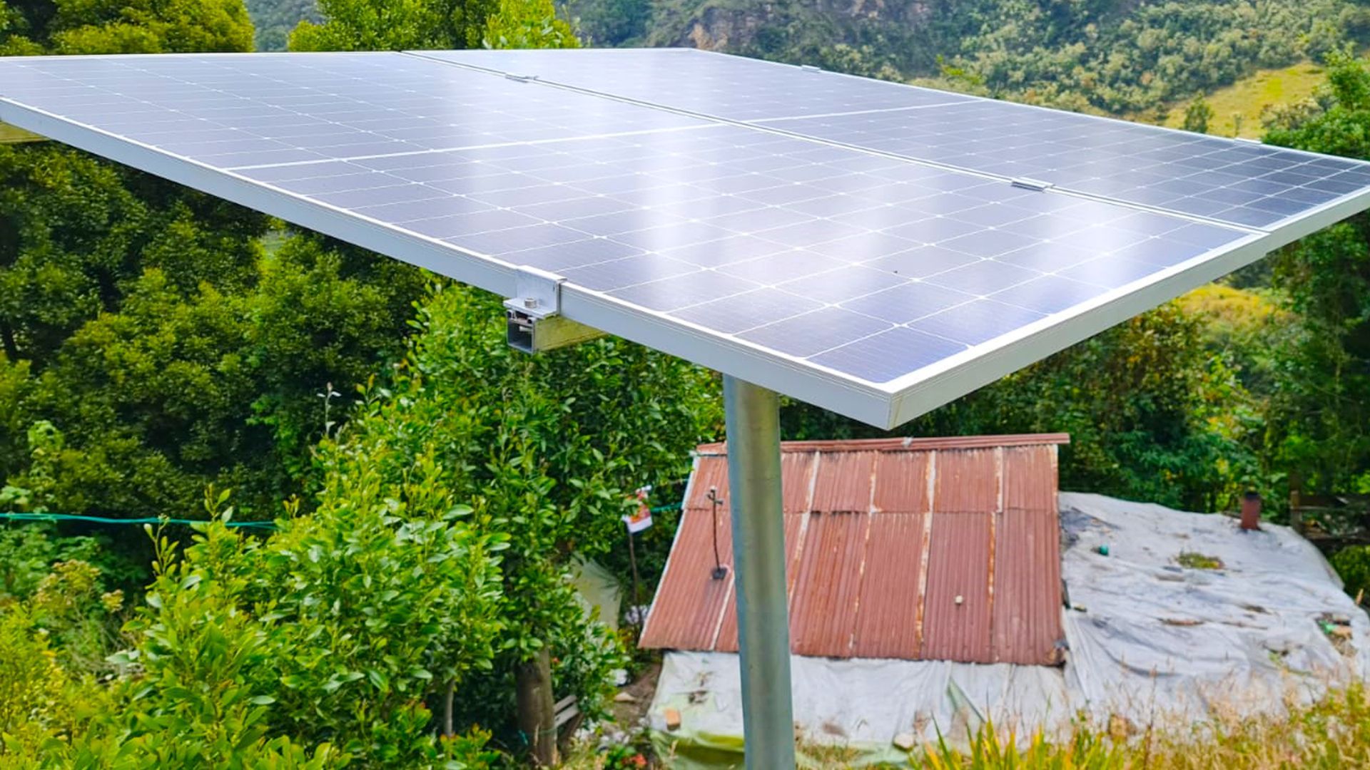 Un panel solar está situado en lo alto de un poste delante de una casa.