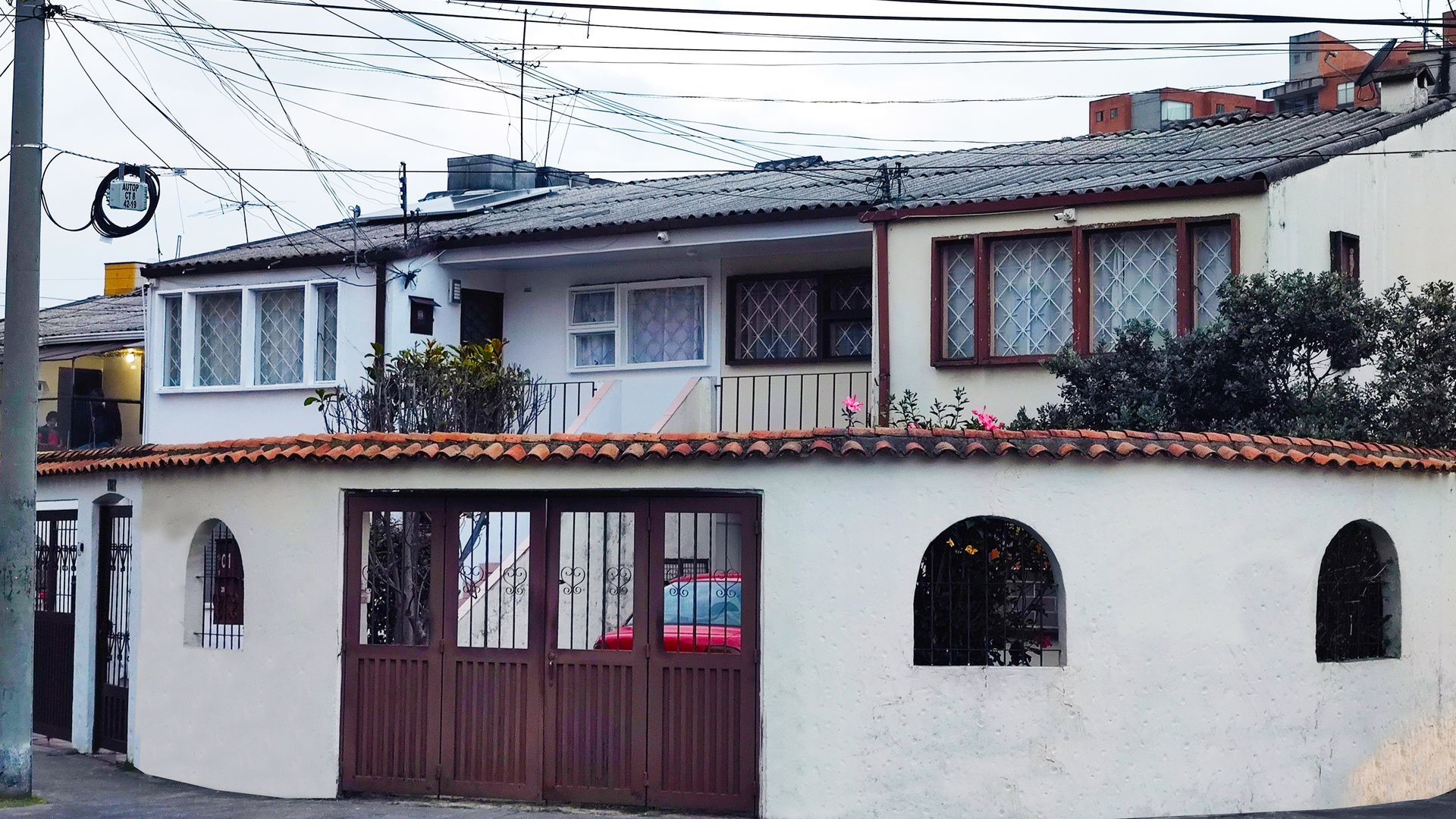 Una casa blanca con una puerta de garaje marrón y ventanas arqueadas.
