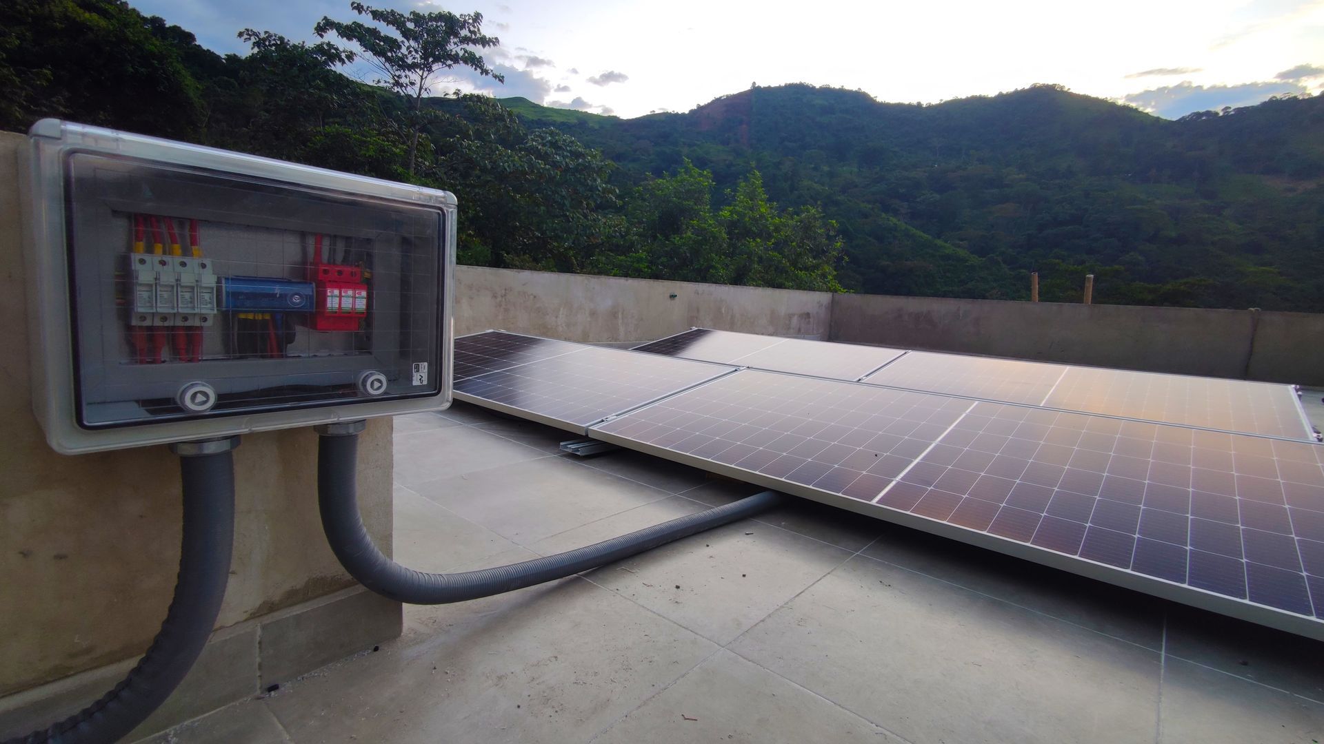 Una fila de paneles solares en un tejado con montañas al fondo.