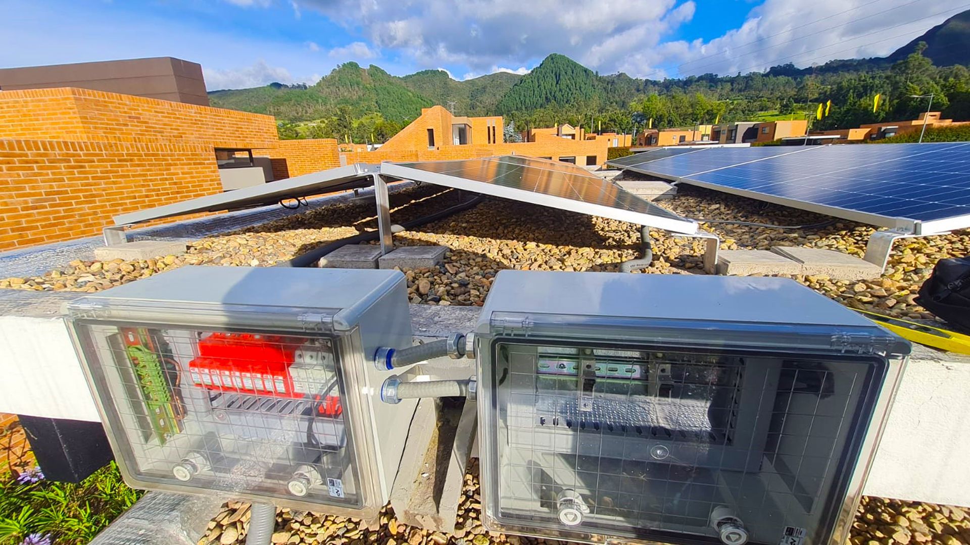 Un par de cajas colocadas encima de un techo con paneles solares en el fondo.