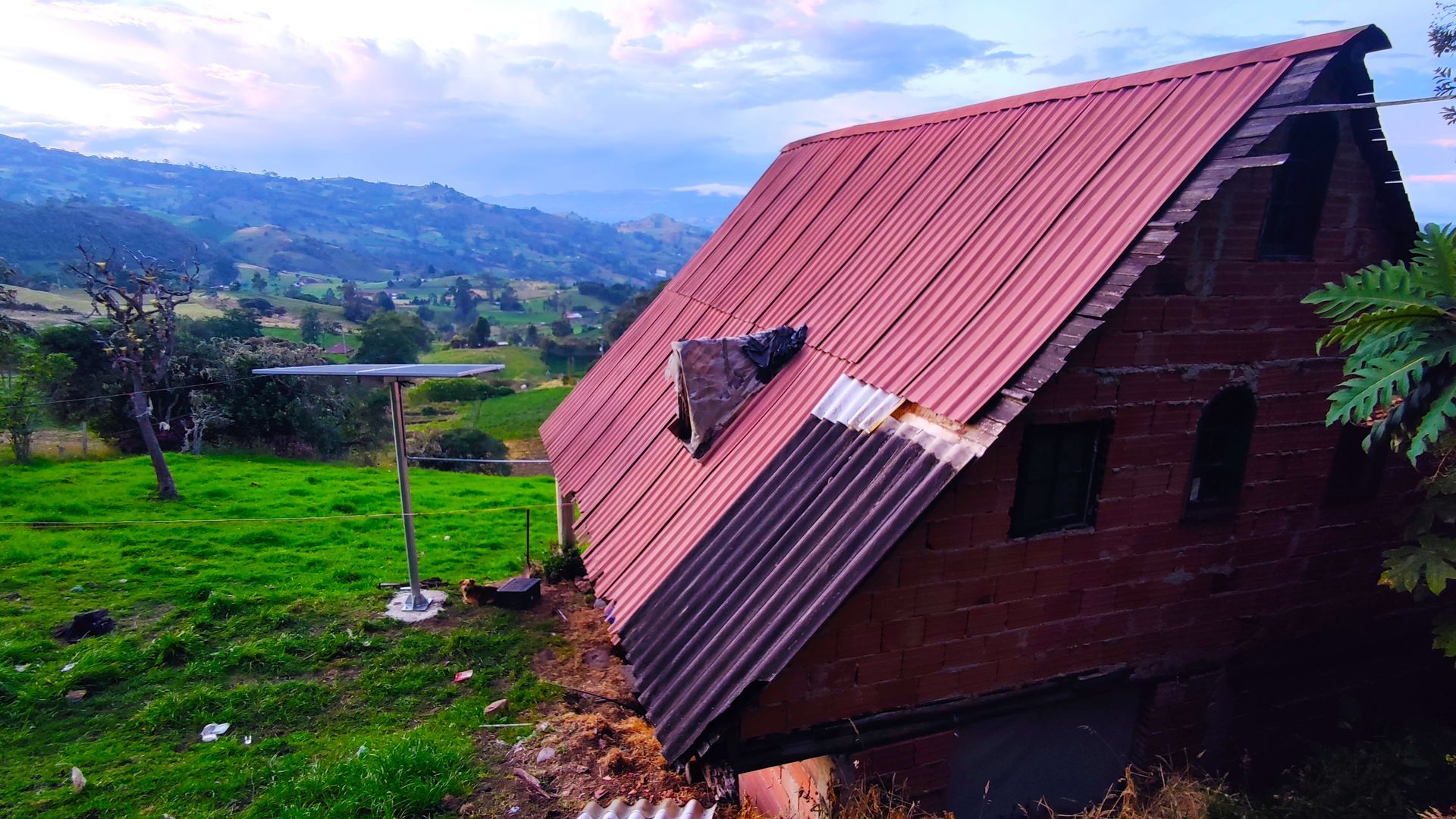 Una pequeña casa con techo rojo se encuentra en medio de un campo de hierba.