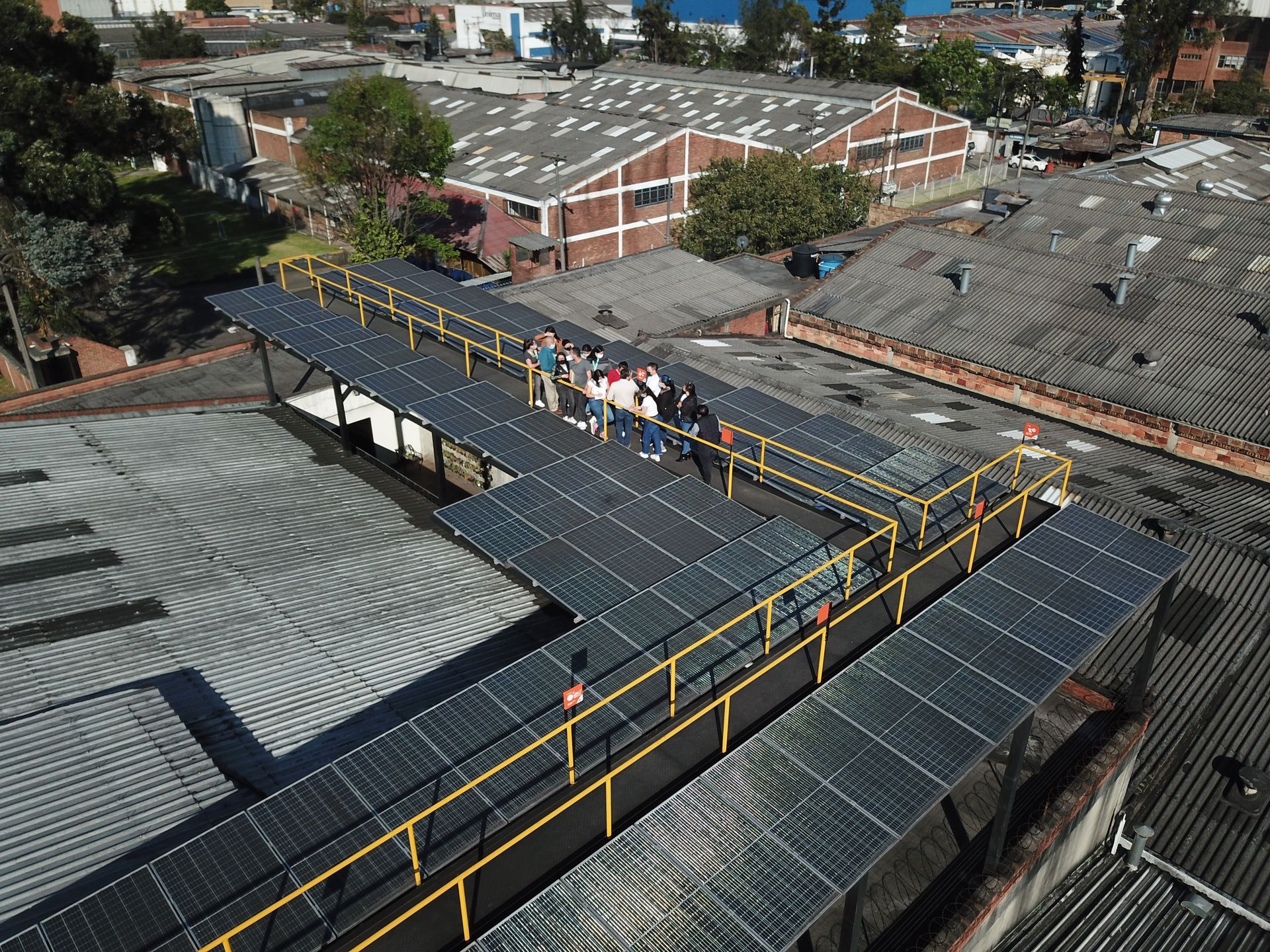 Un grupo de personas se encuentra de pie encima de un tejado con paneles solares.