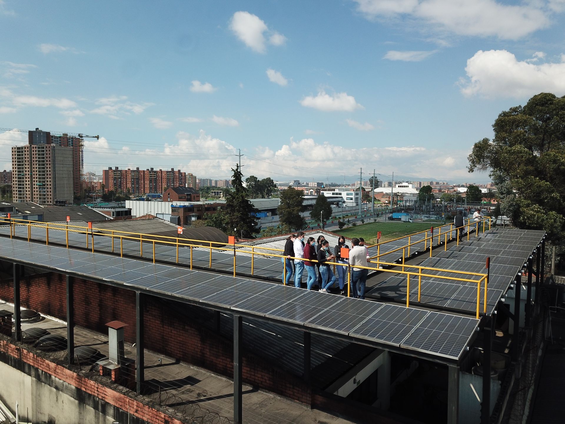 Un grupo de personas se encuentra de pie encima de un tejado con paneles solares.