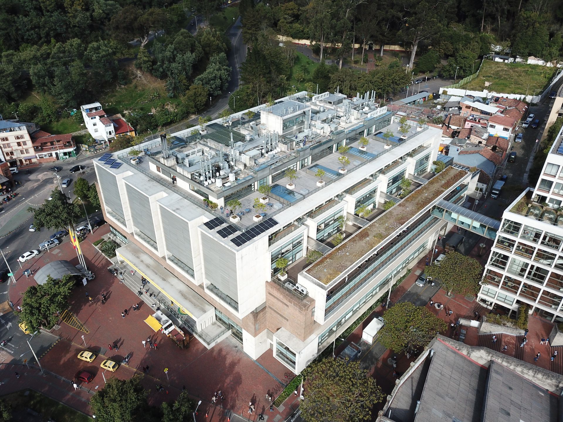 Una vista aérea de un gran edificio con techo verde rodeado de árboles.