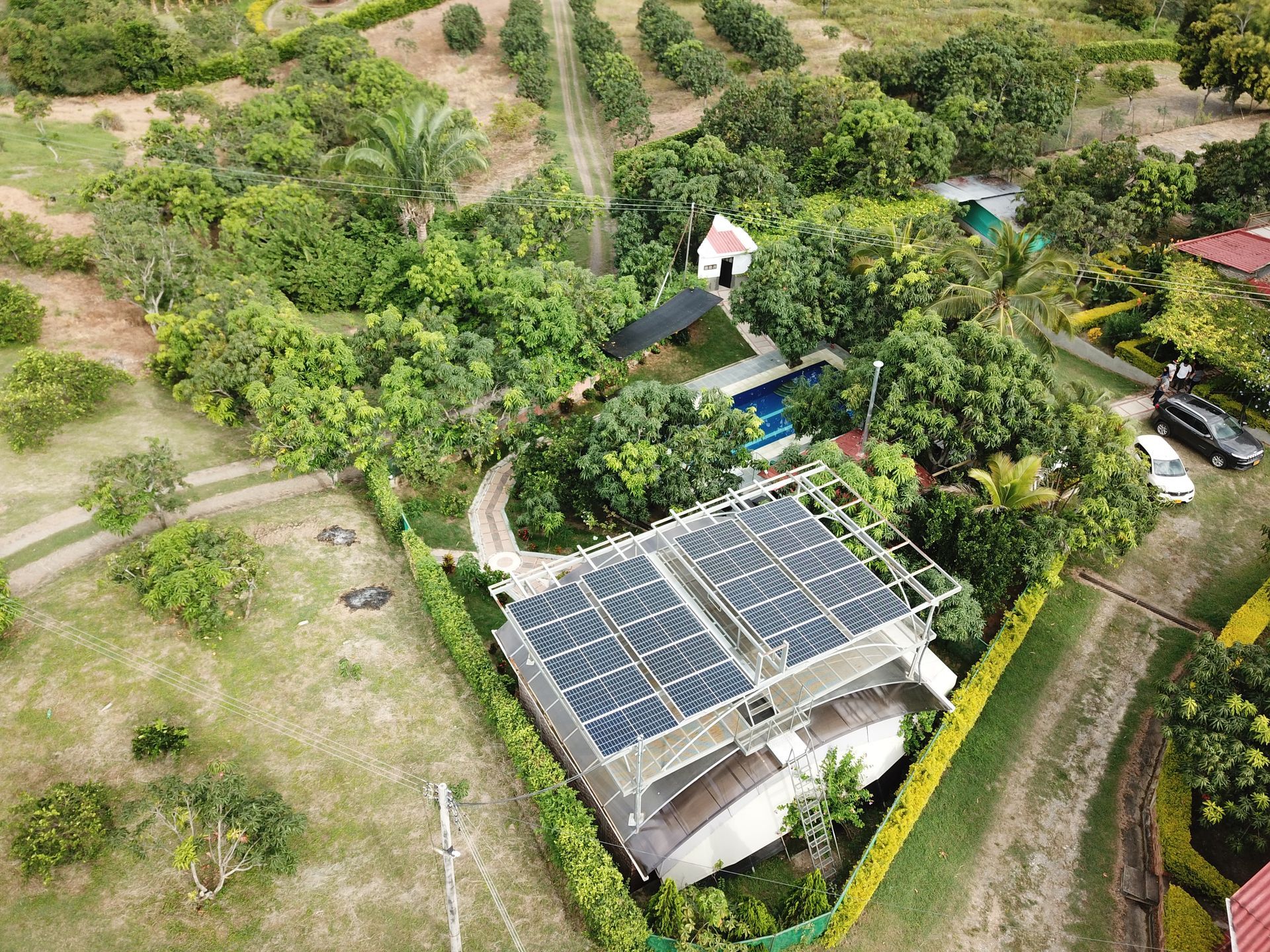 Una vista aérea de una casa con paneles solares en el techo rodeada de árboles.