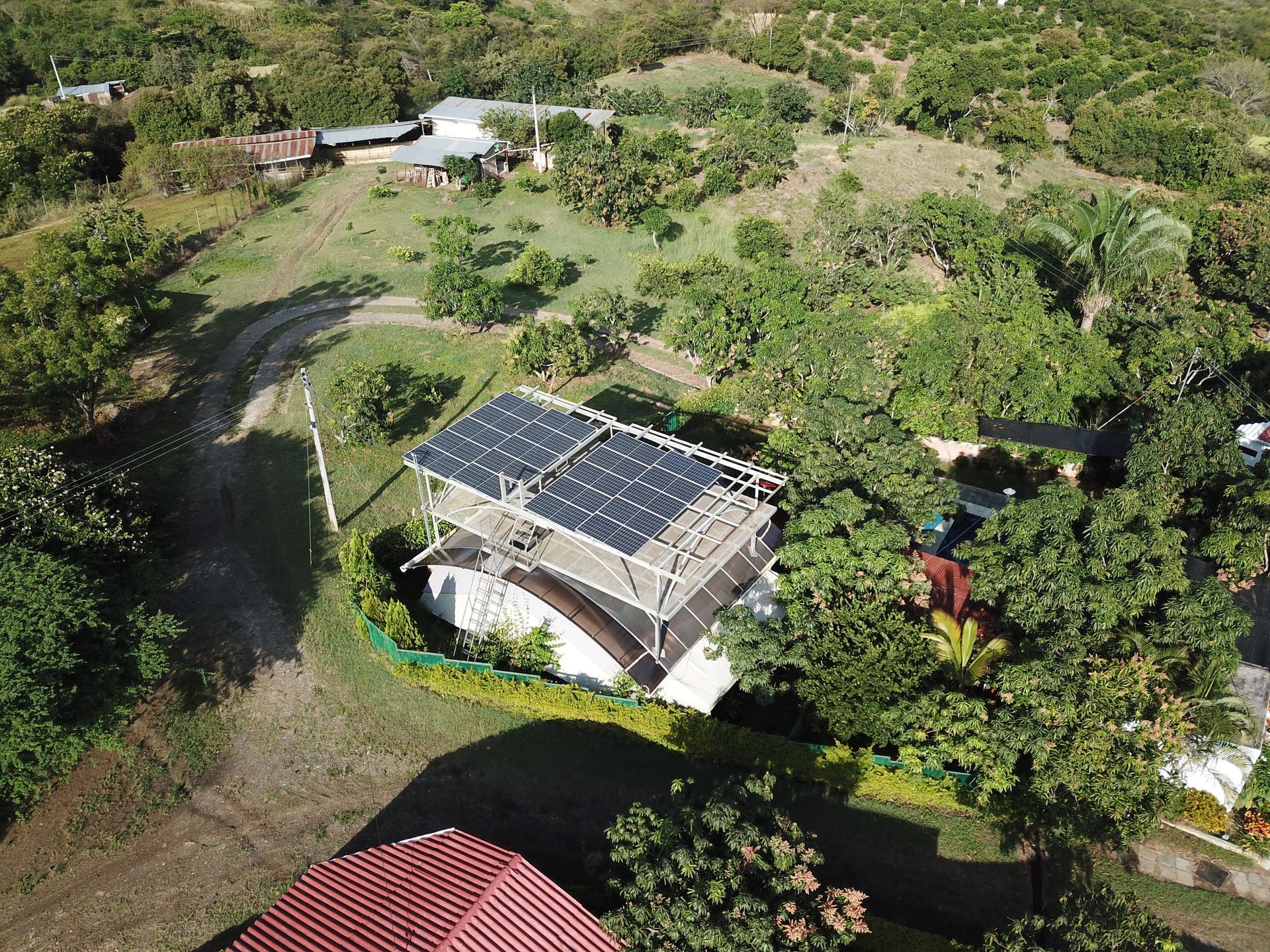 Una vista aérea de una casa con paneles solares en el techo rodeada de árboles.