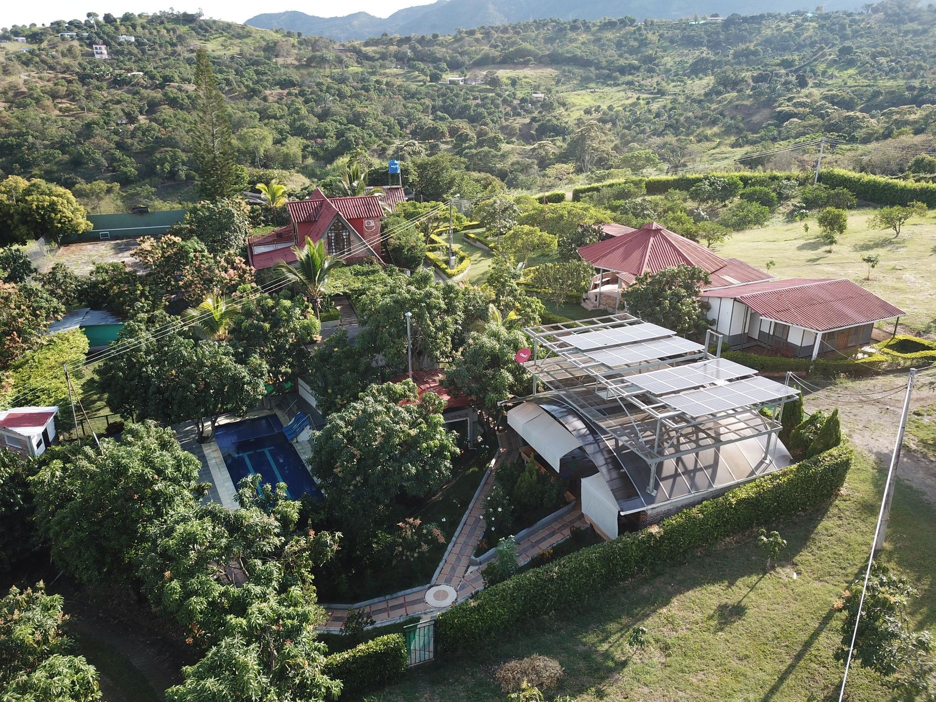 Una vista aérea de una casa con piscina en medio de un exuberante campo verde.