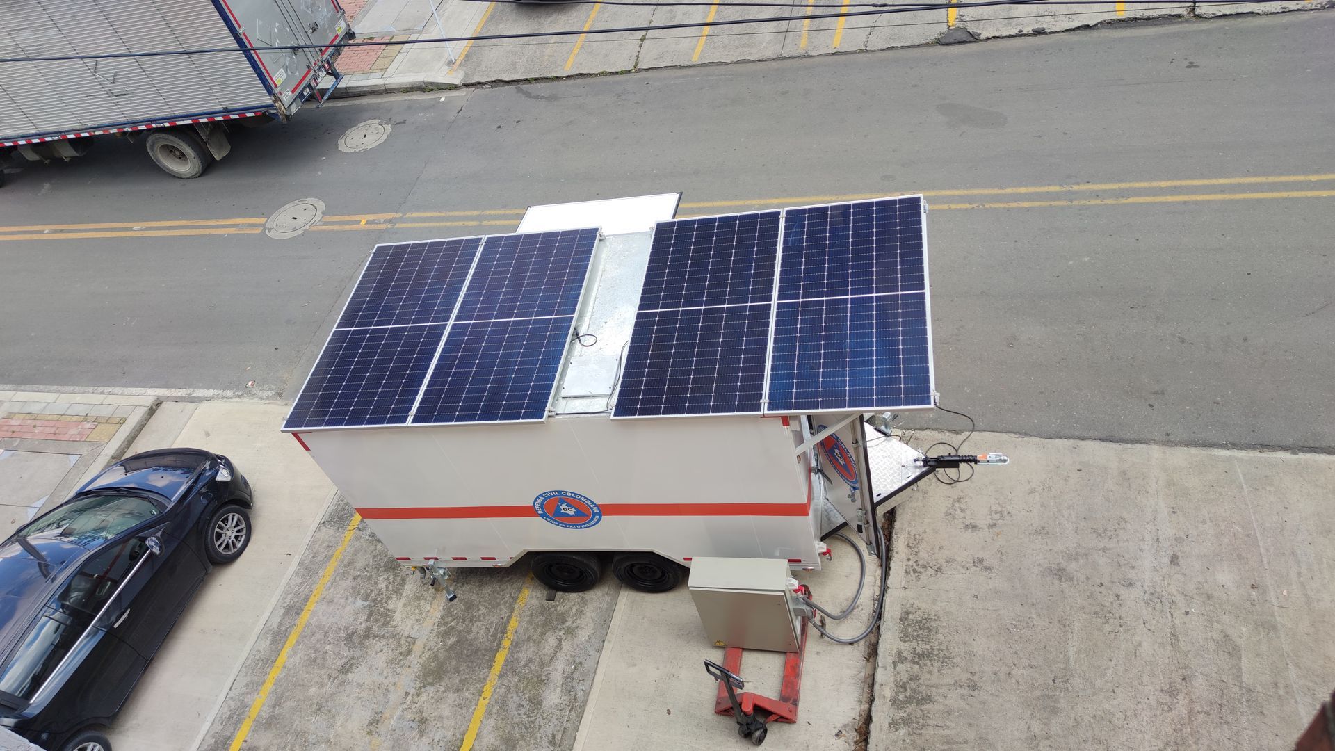 Un remolque con paneles solares en la parte superior está estacionado en un estacionamiento.