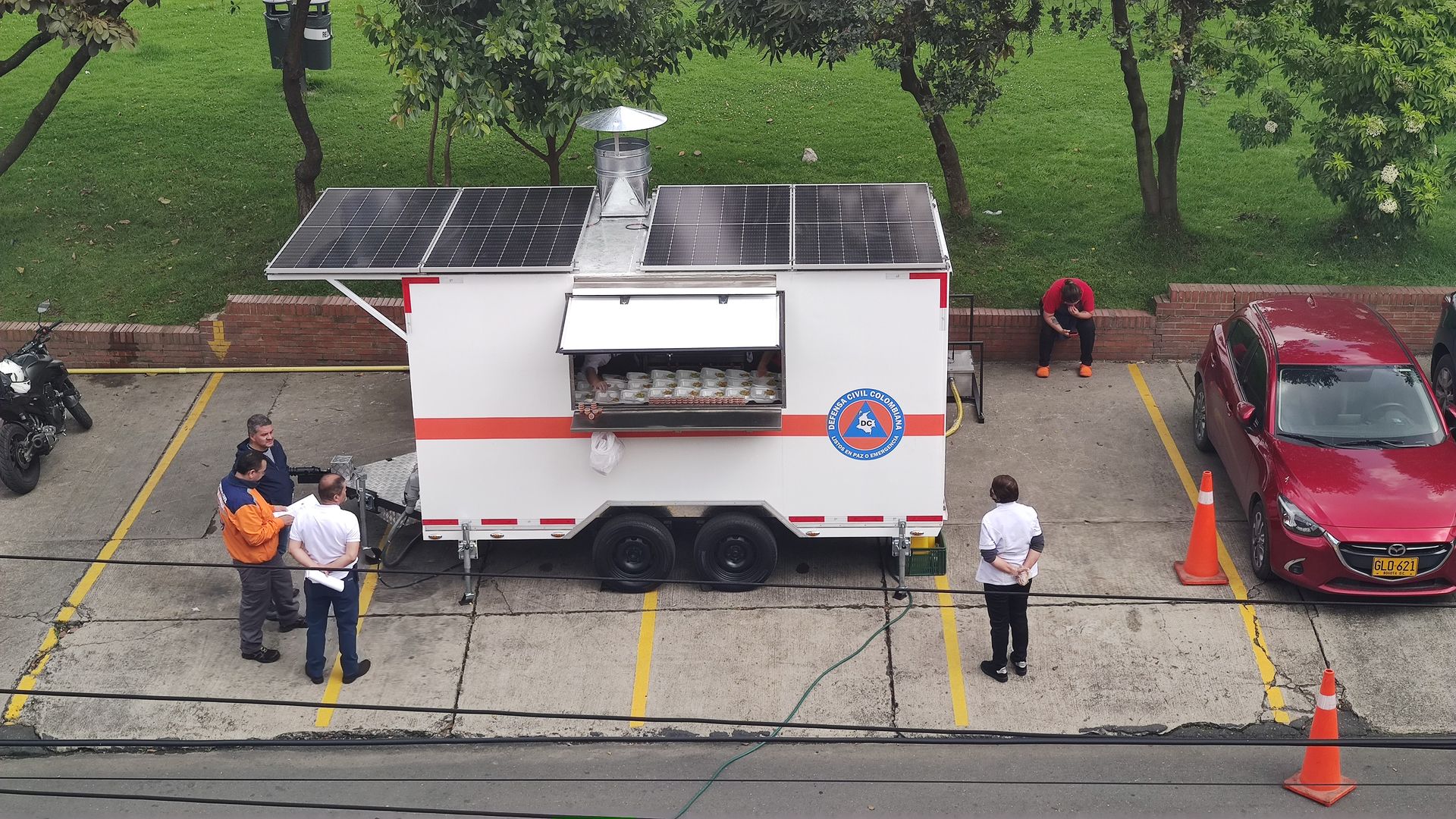 Un camión de comida está estacionado en un estacionamiento al lado de un auto rojo.