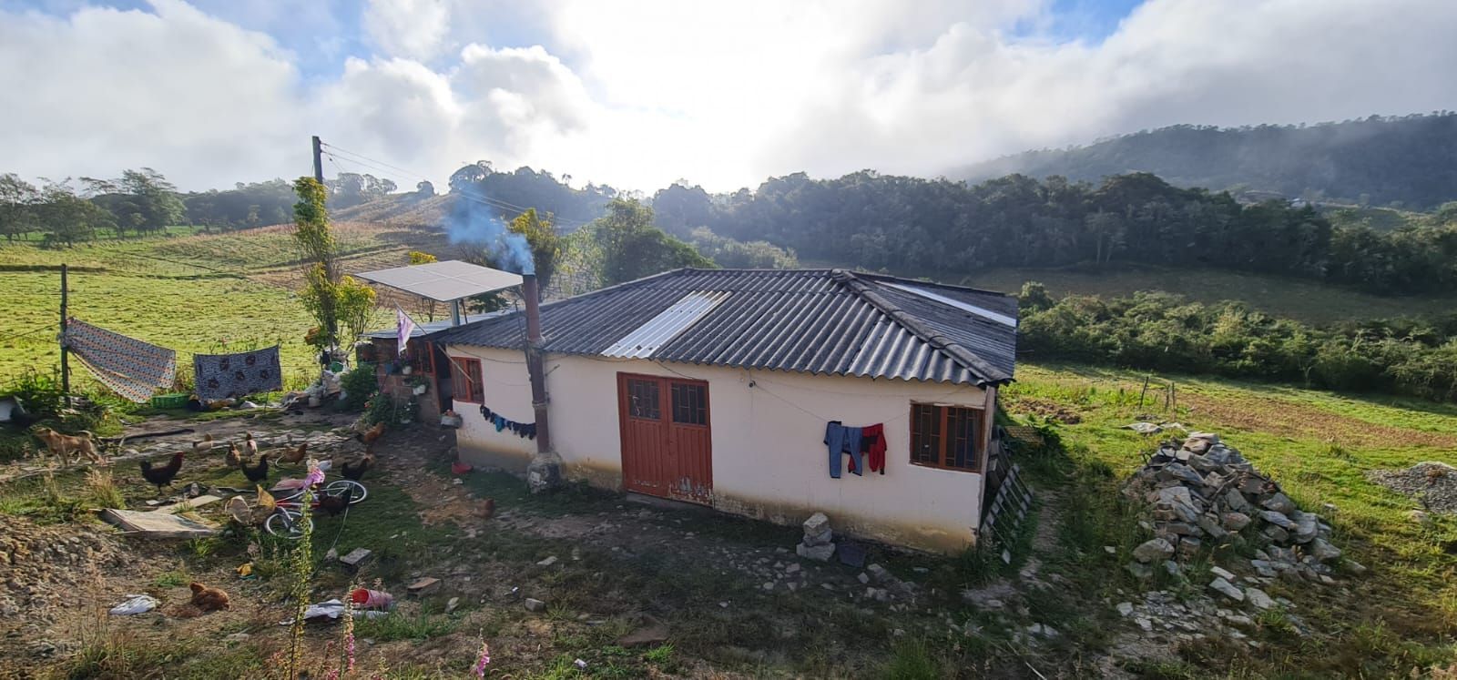 Una pequeña casa está situada en la cima de una colina en medio de un campo.