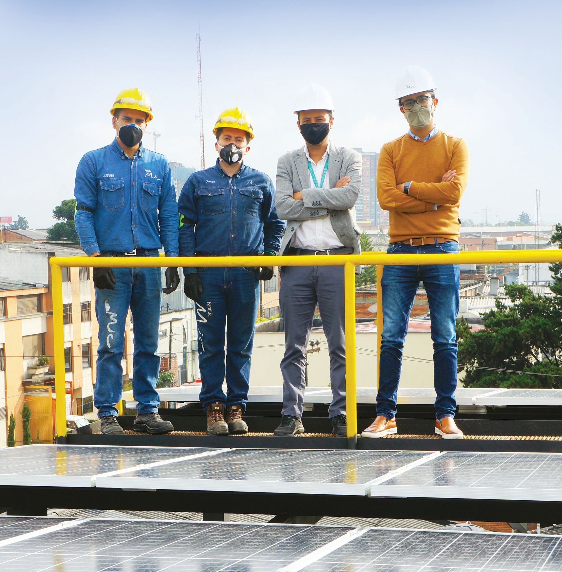 Energía renovable Cuatro personas con cascos y máscaras se encuentran sobre un techo con paneles solares.