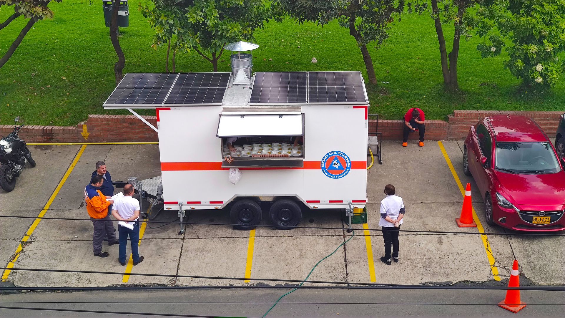 Un camión de comida está estacionado en un estacionamiento al lado de un auto rojo.