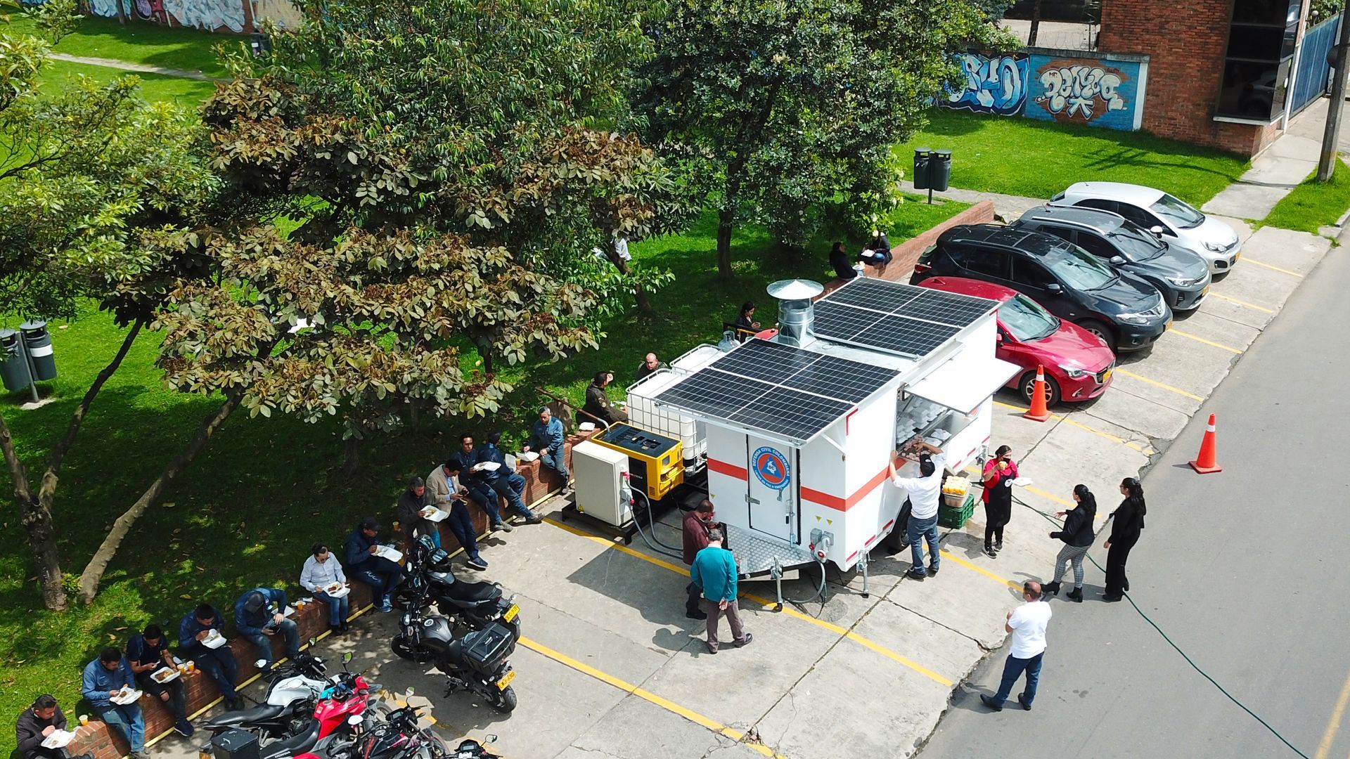 Un grupo de personas están paradas alrededor de un remolque en un estacionamiento.