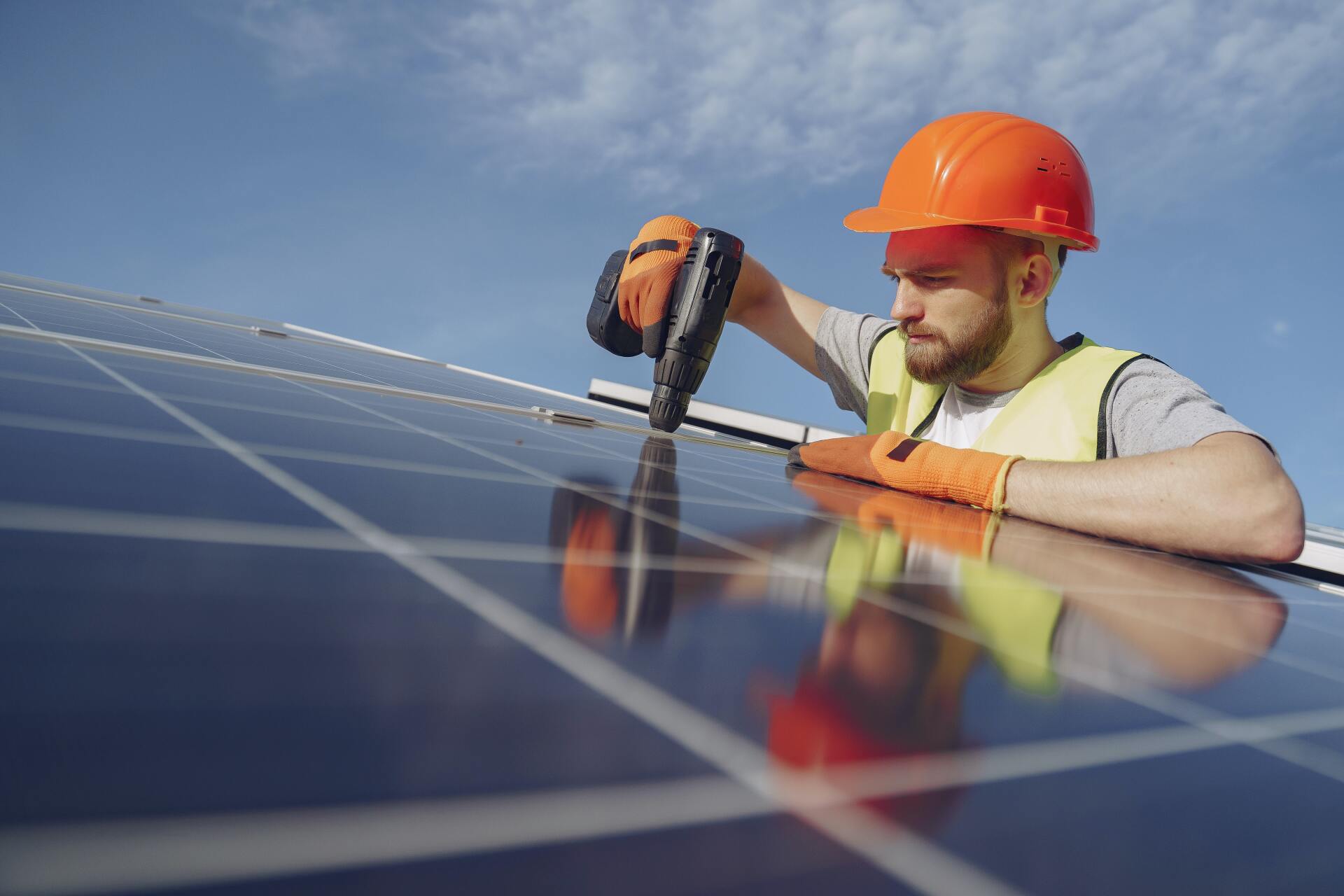 Un hombre está trabajando en un panel solar con un taladro.