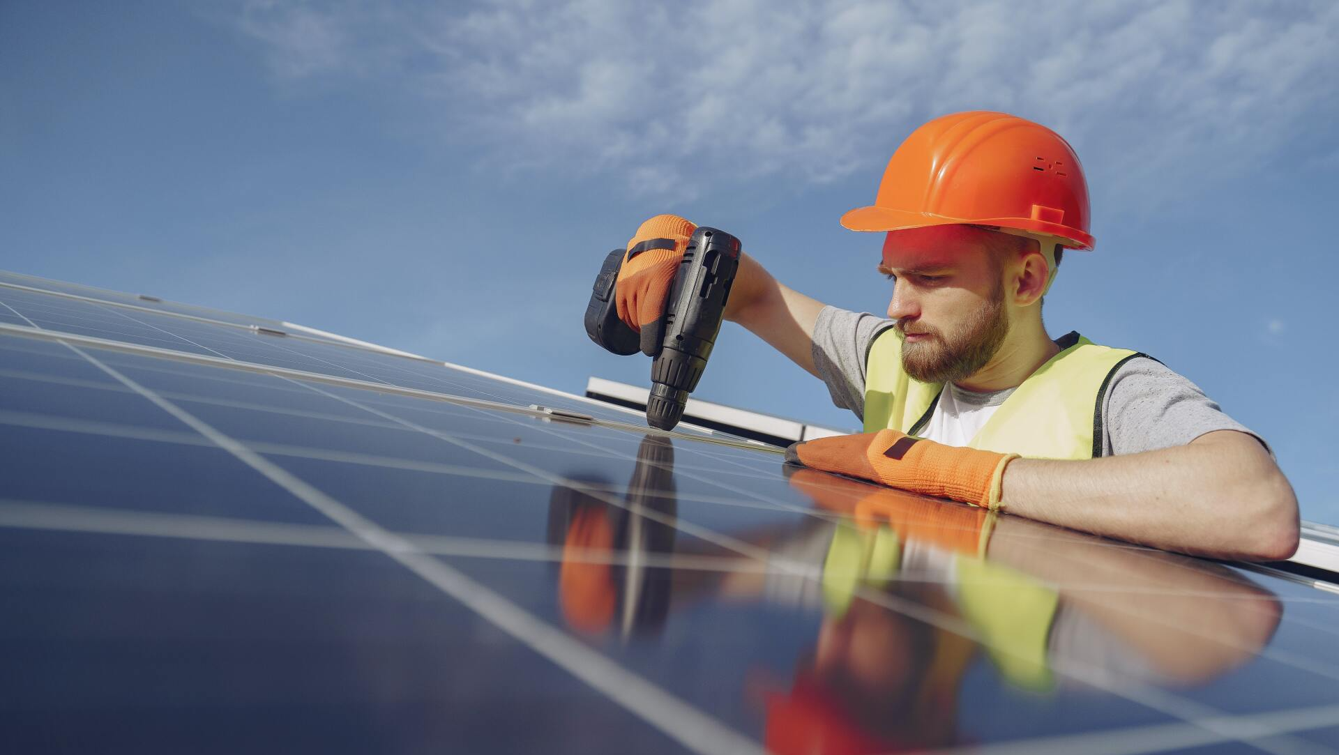 Un hombre está trabajando en un panel solar con un taladro.