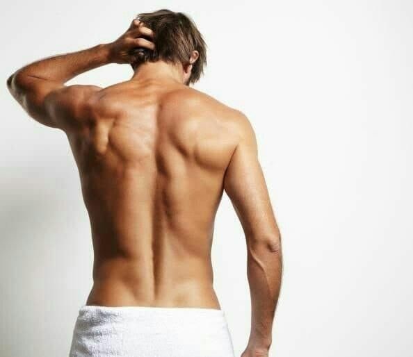 La espalda de un hombre sin camisa con una toalla alrededor de su cintura.