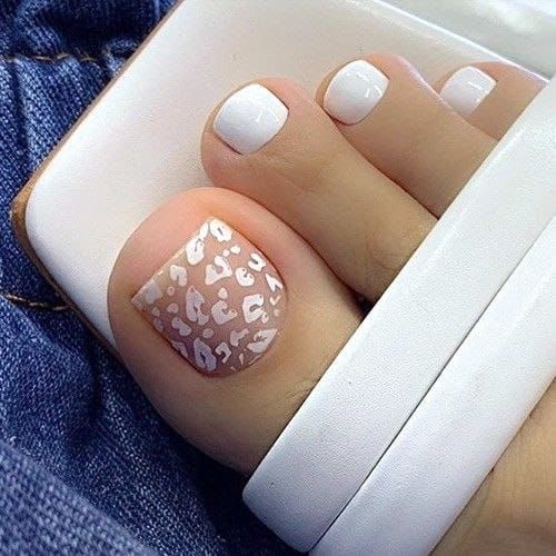 Las uñas de los pies de una mujer están pintadas de blanco con un estampado de leopardo.