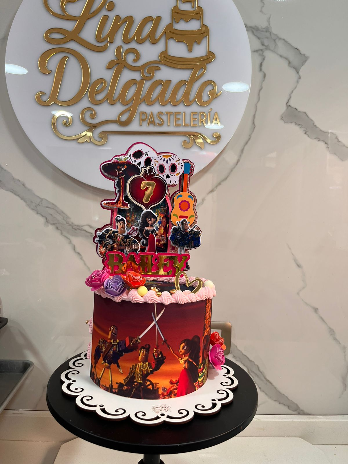 Tarta decorada para el séptimo cumpleaños con temática del Rey León y adorno dorado de “Lina Delgado” sobre una base negra.