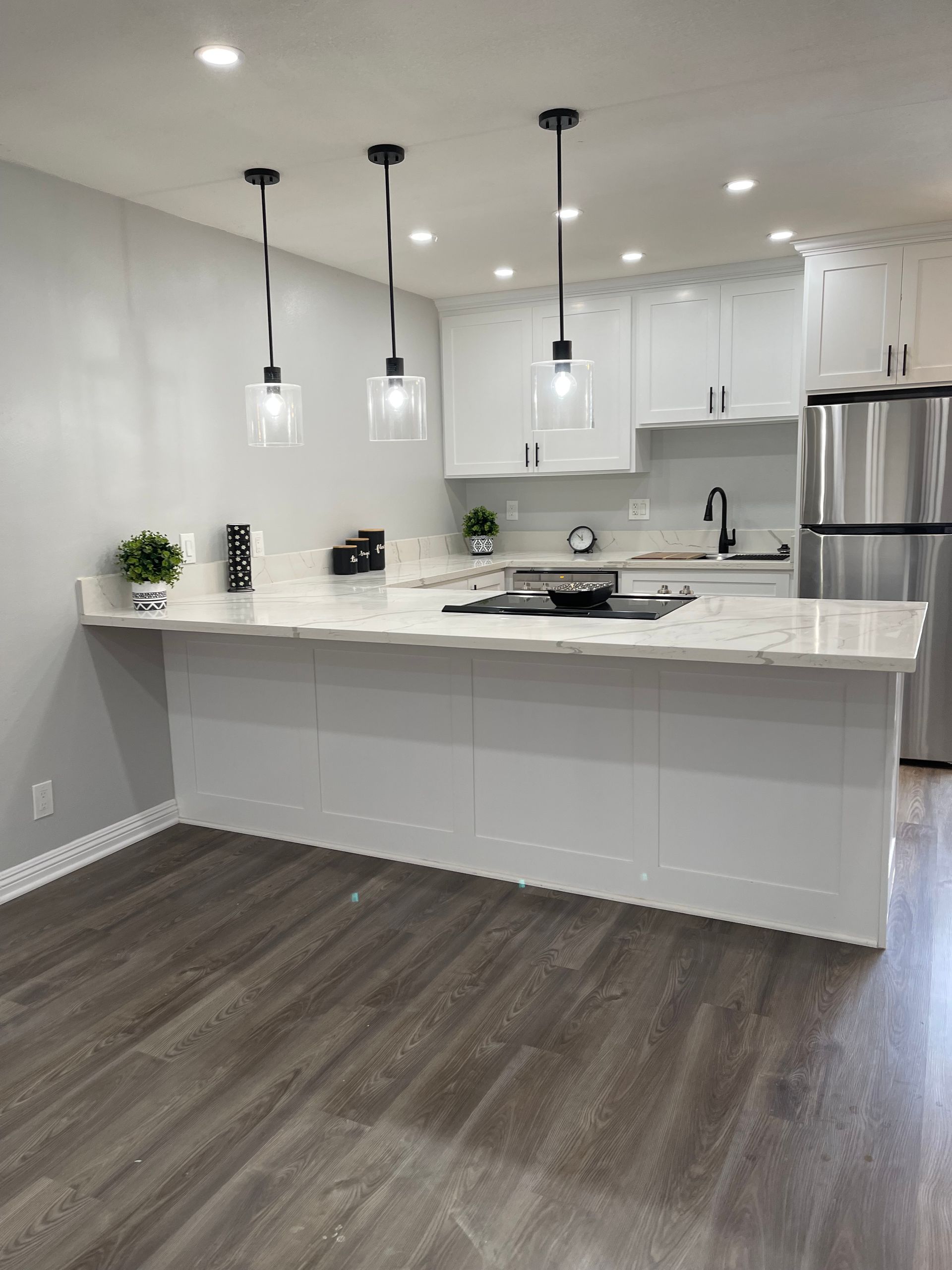 A kitchen with white cabinets , stainless steel appliances , and a large island.
