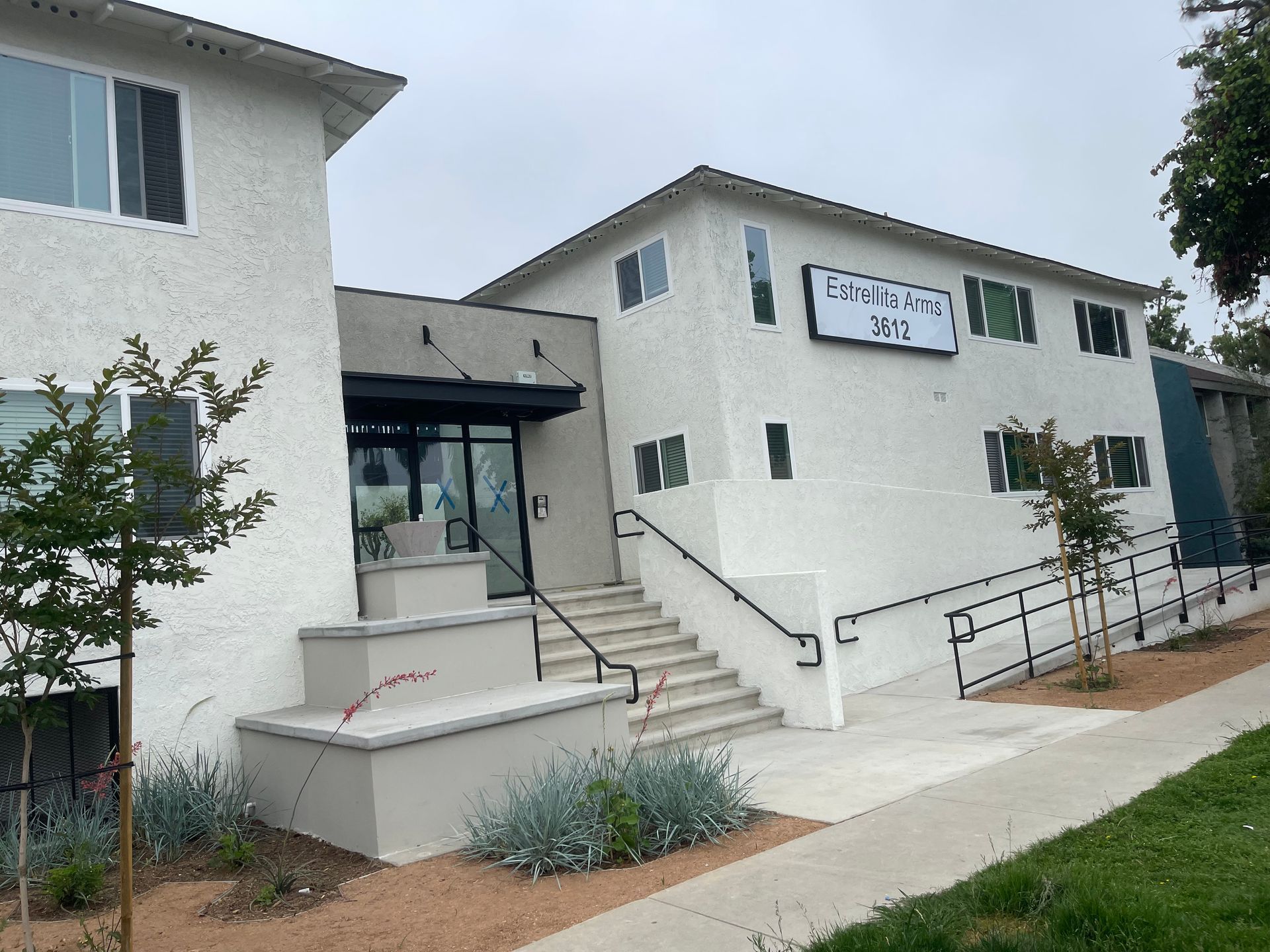 A white apartment building with stairs leading up to the entrance.