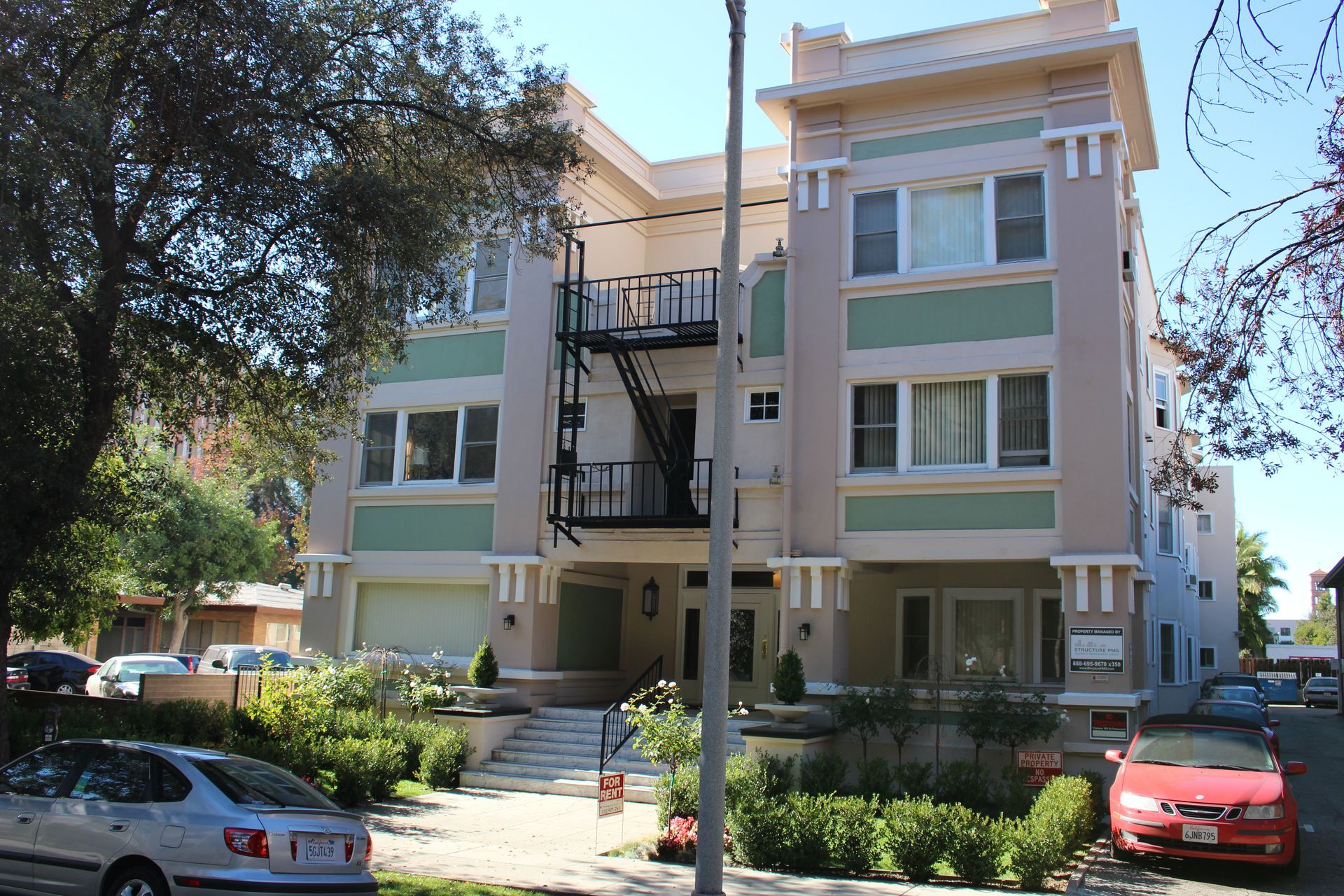 A pink and green apartment building with a fire escape
