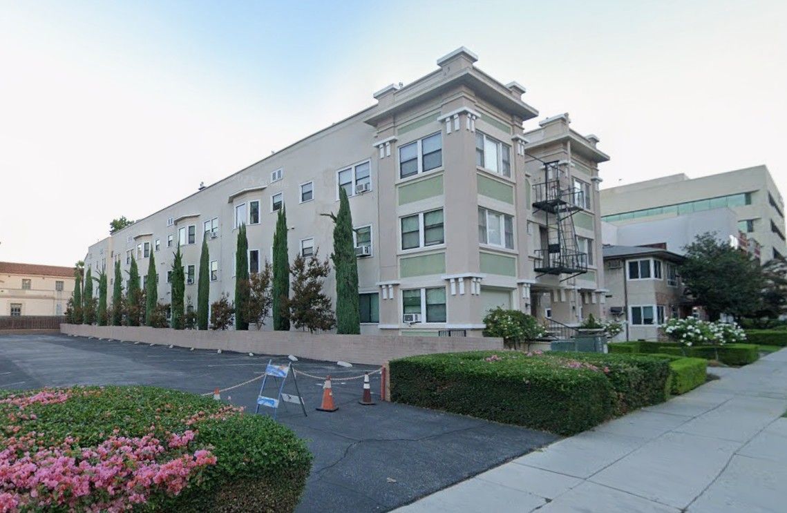 A large apartment building with a lot of windows and trees in front of it.