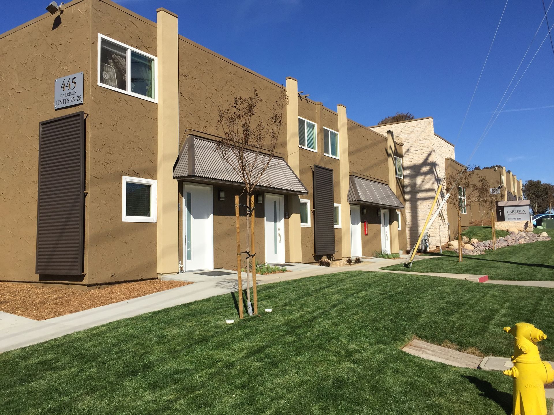 A row of apartment buildings with a yellow fire hydrant in front of them.