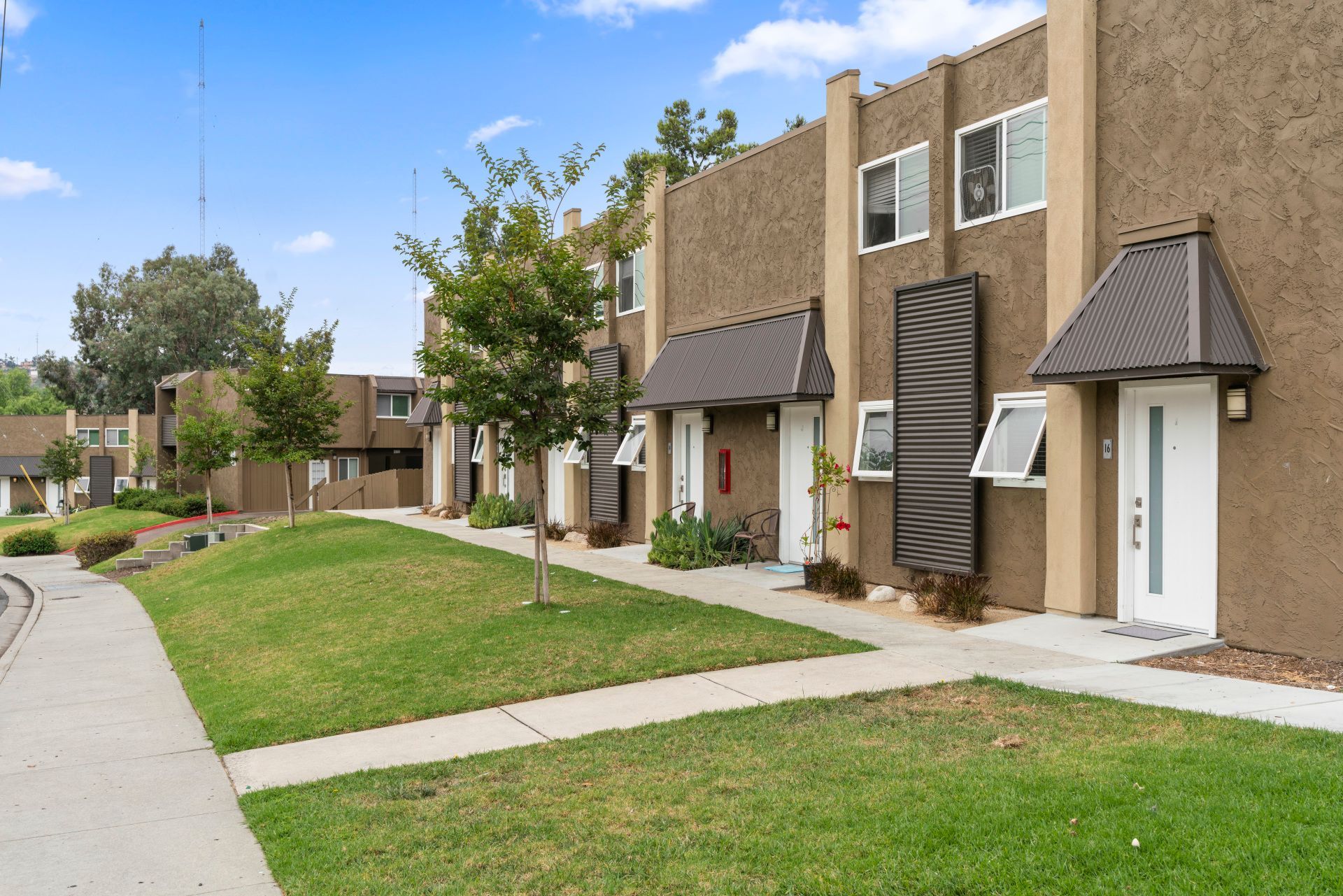 A row of apartment buildings with a sidewalk in front of them.