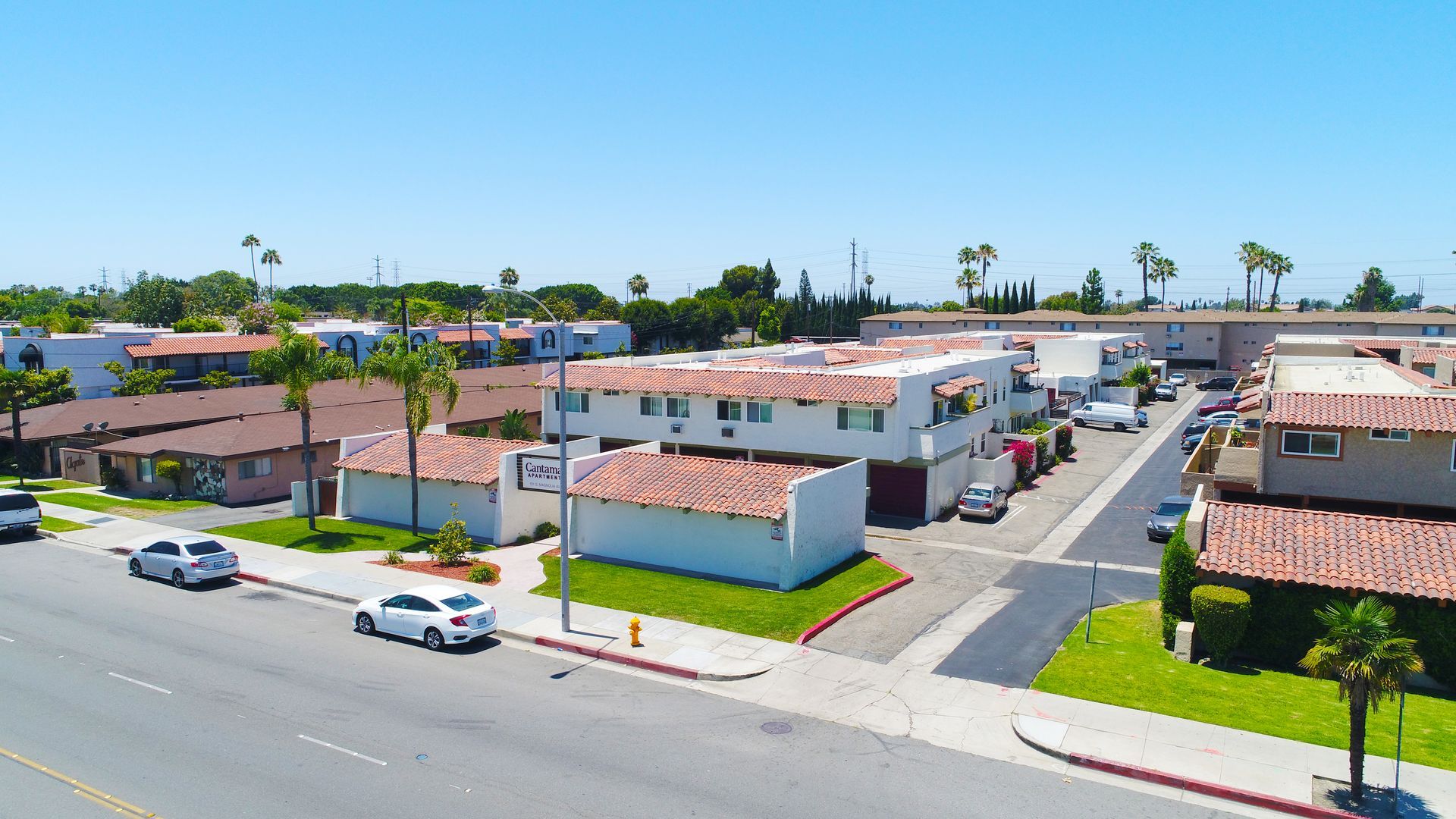 An aerial view of a residential area with cars parked on the side of the road.