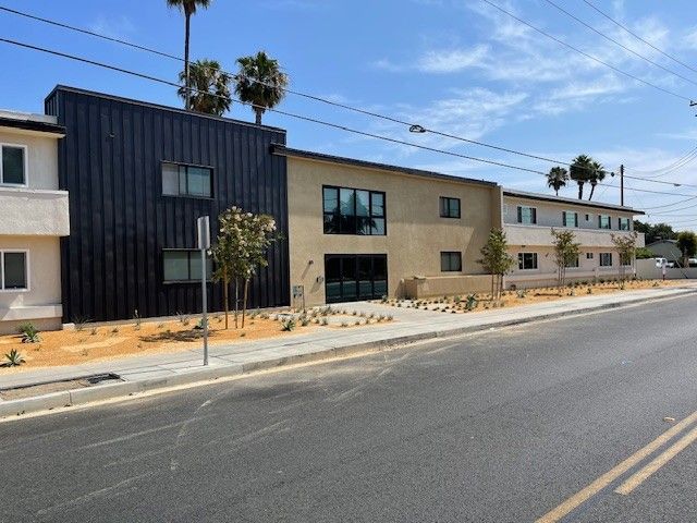 A row of apartment buildings along a street with palm trees in the background