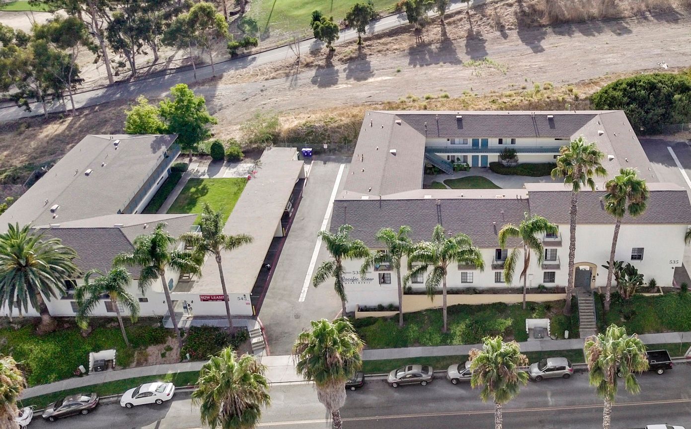 An aerial view of a building with palm trees in front of it