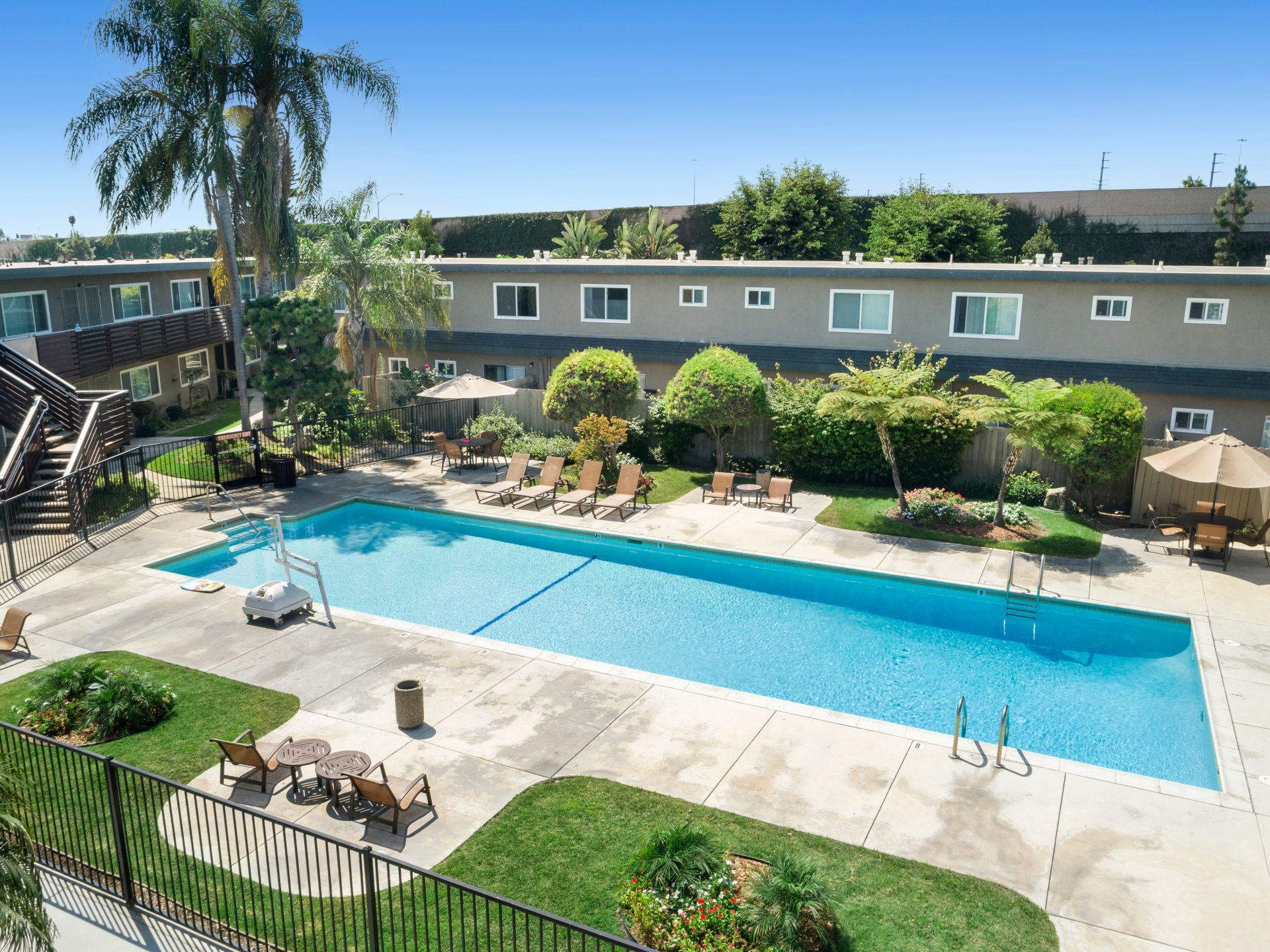 A large swimming pool surrounded by chairs and umbrellas in front of a building