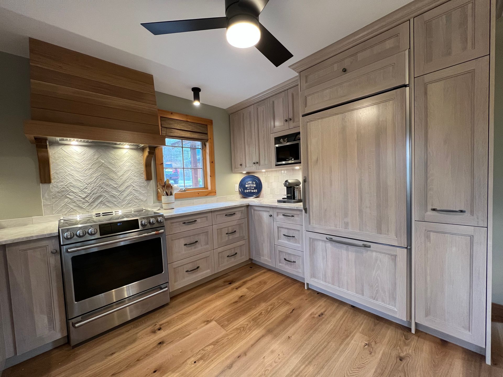 A kitchen with wooden cabinets , stainless steel appliances , and a ceiling fan.