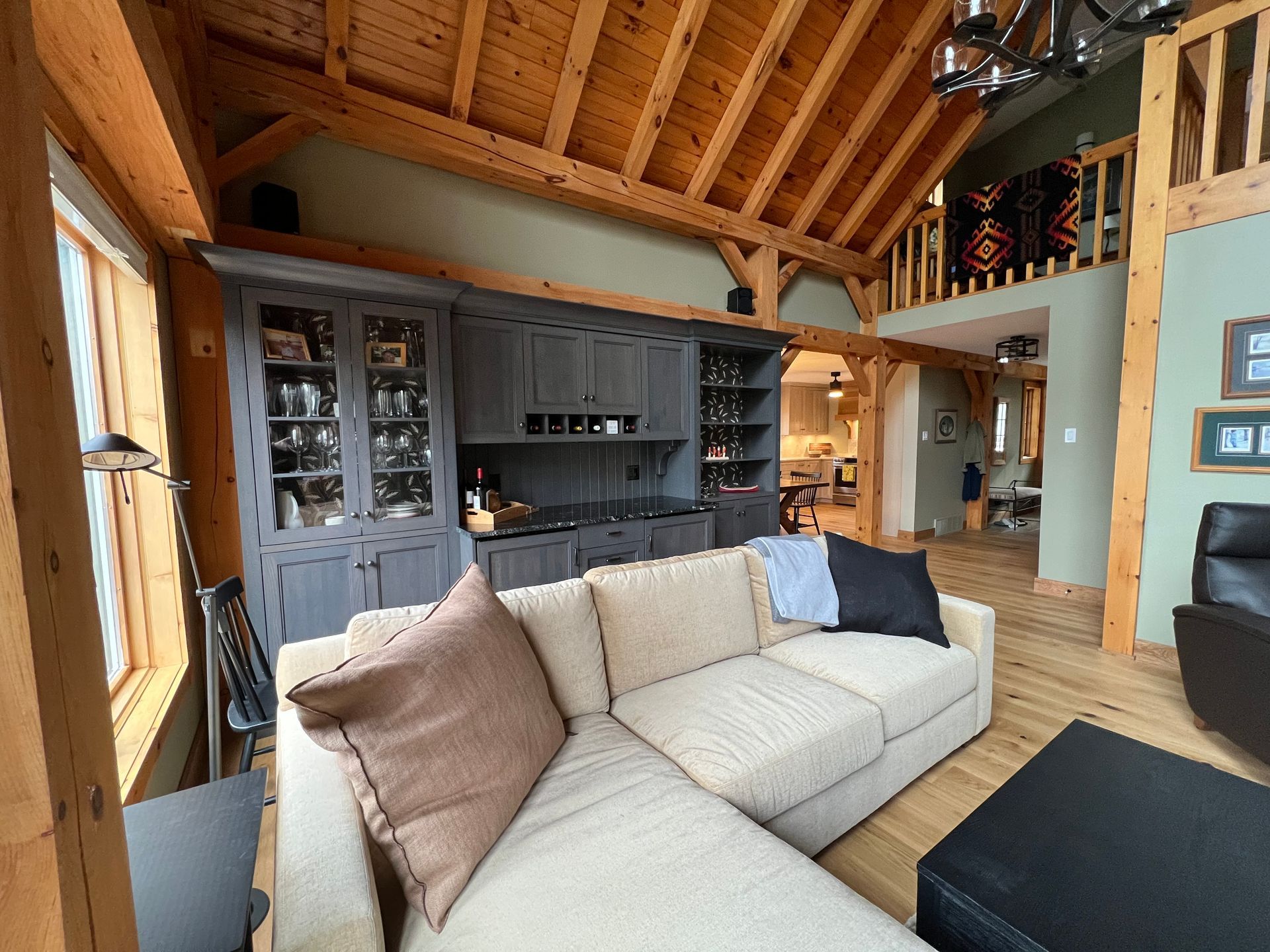 A living room with a couch , chairs , and a wooden ceiling.