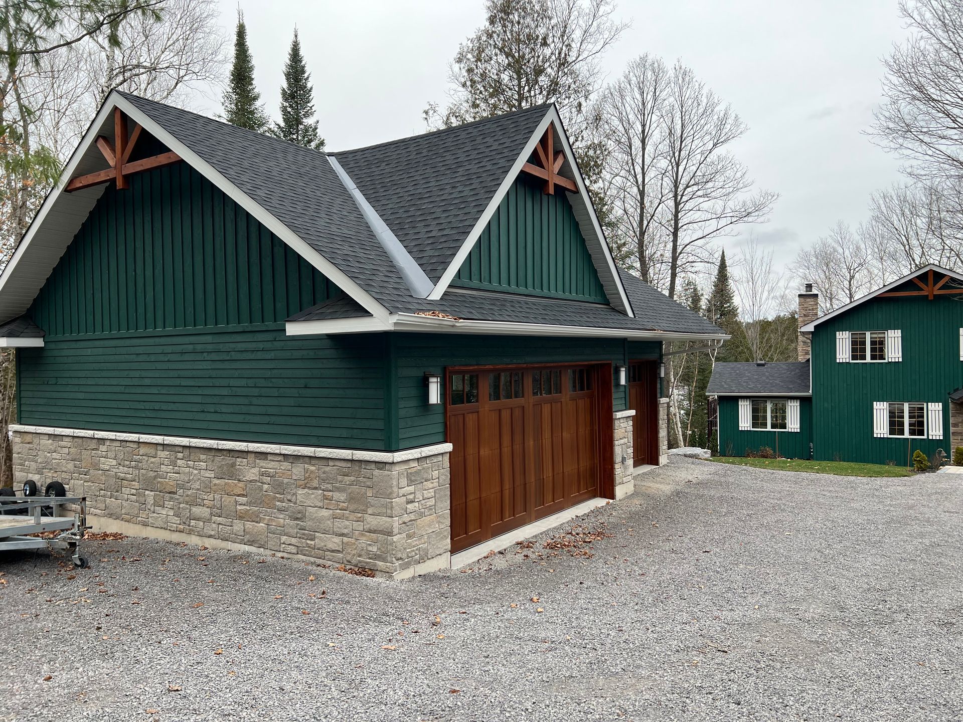 A green house with a large garage next to it.