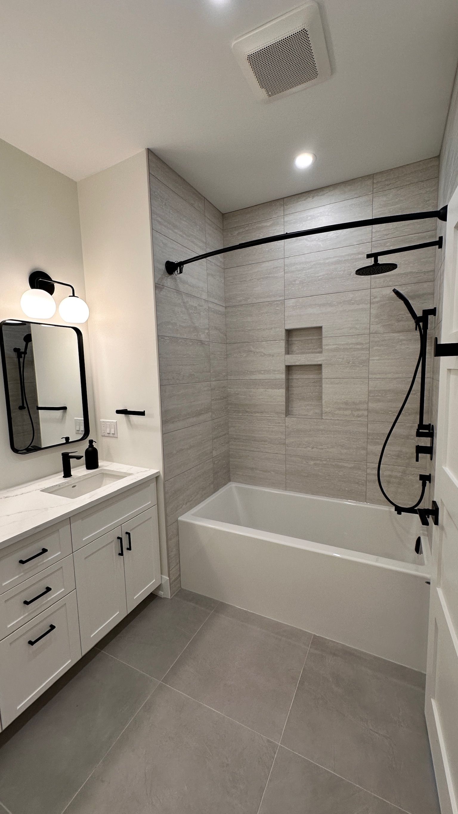 A bathroom with a tub , sink , mirror and shower.