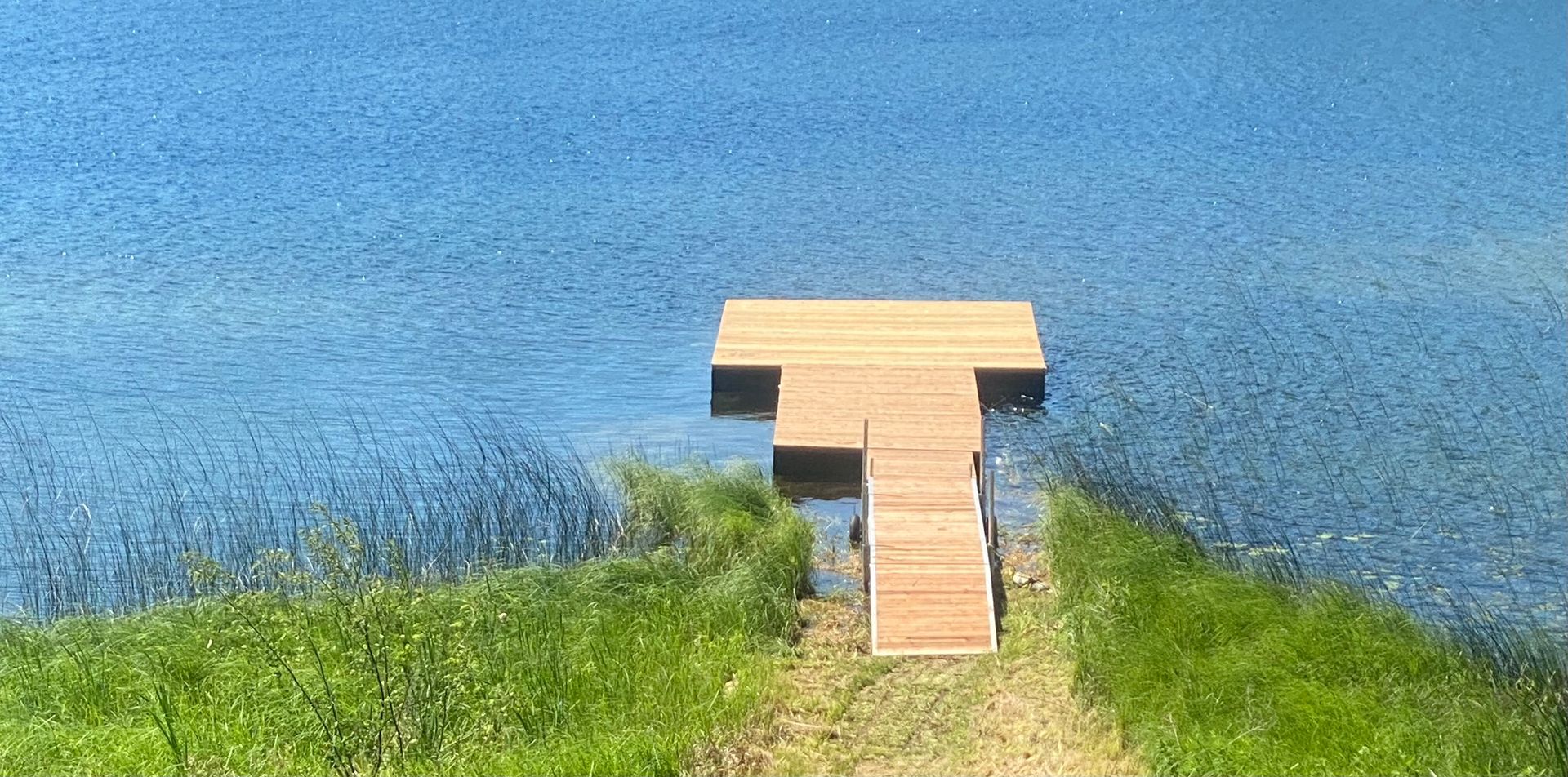 A wooden dock is sitting on a small island in the middle of a lake.