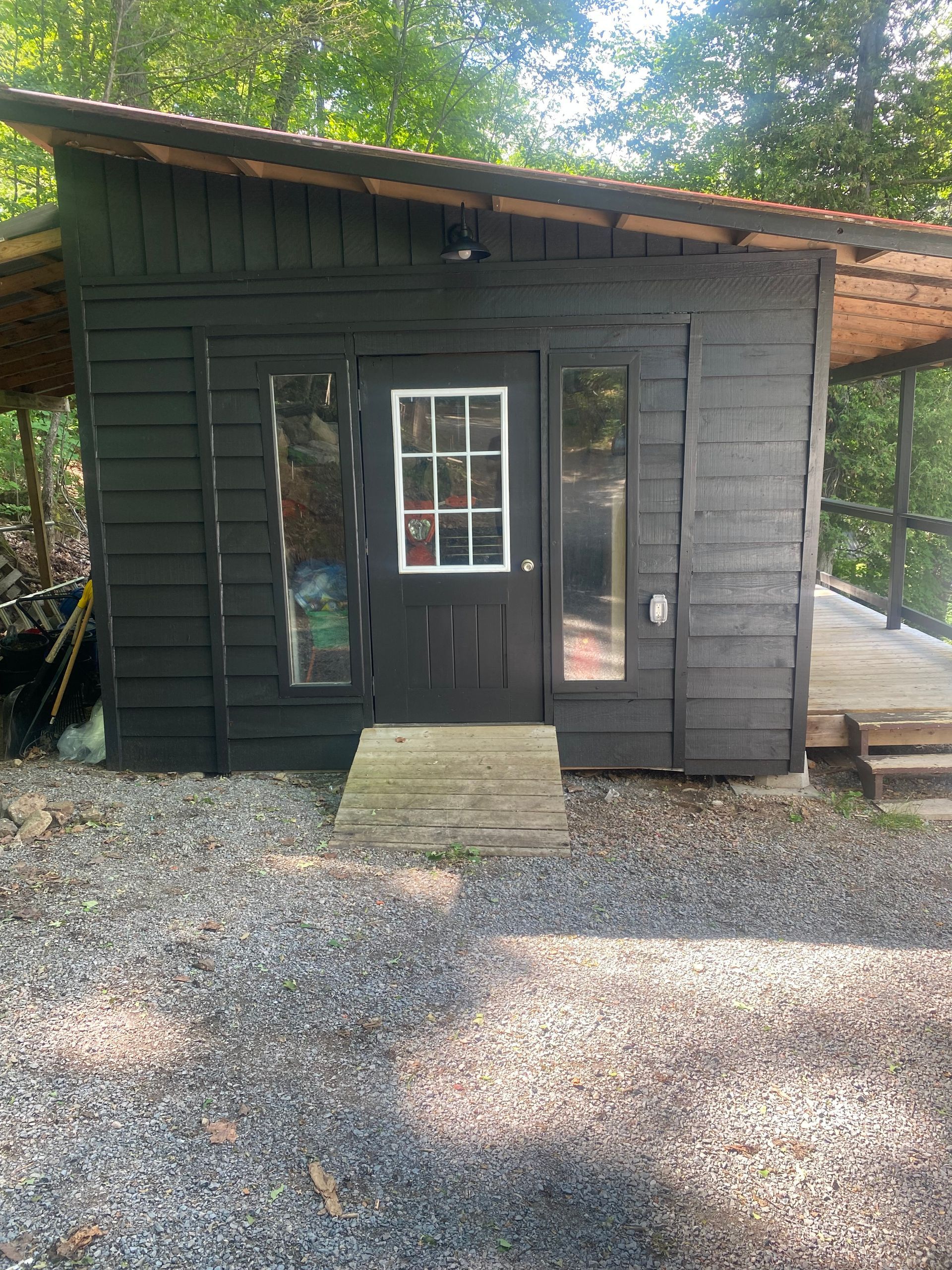 A small black house with a window and a ramp leading to it.