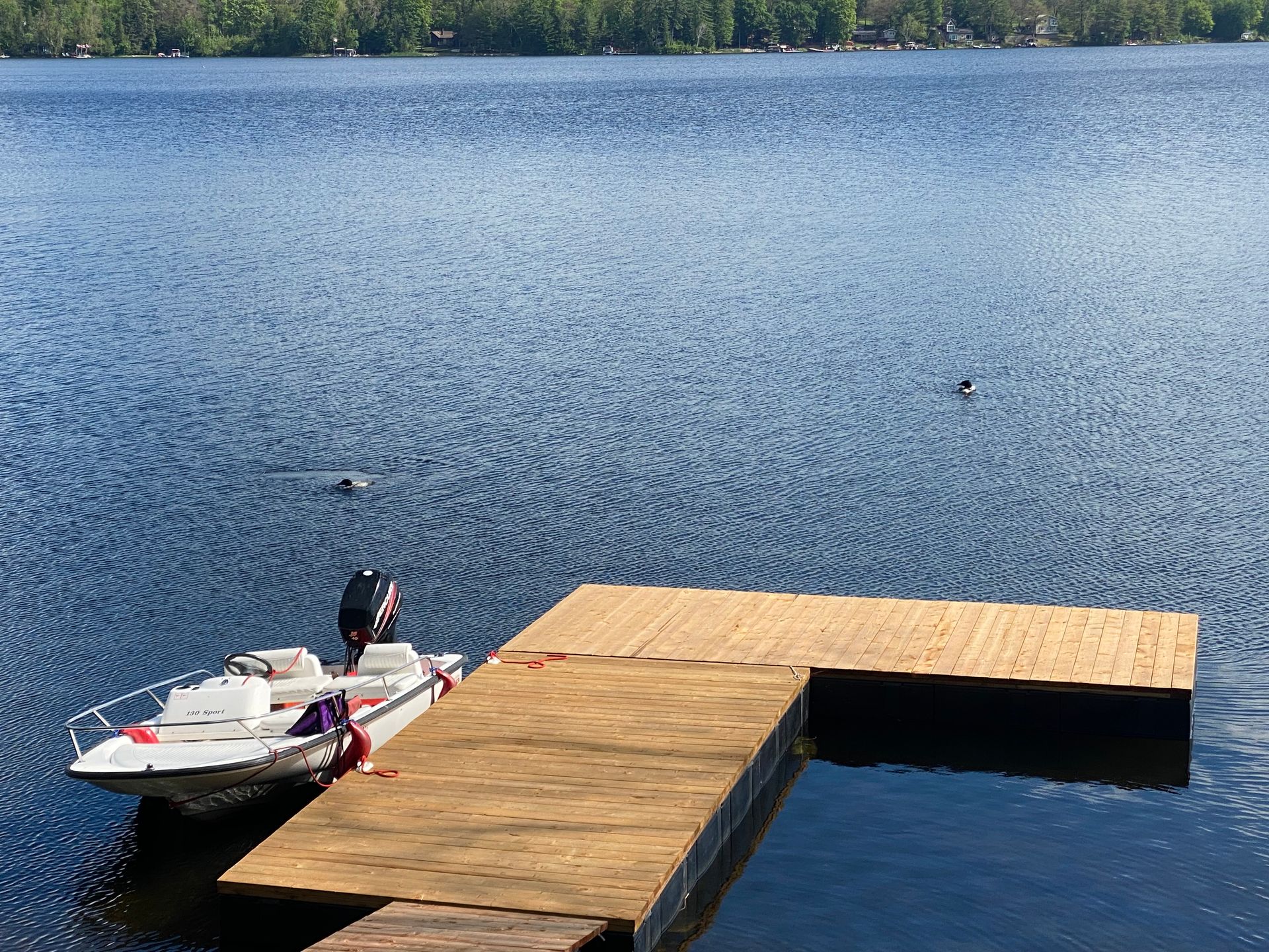 A boat is docked at a wooden dock on a lake.