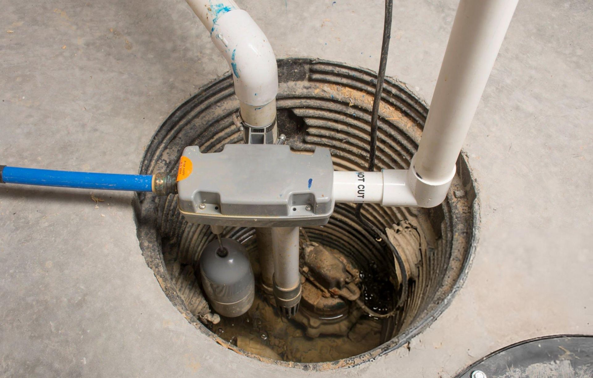 A sump pump is installed in a basement of a home with a water-powered backup system.