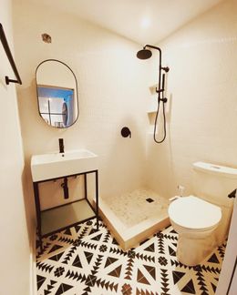 Modern bathroom with black and white patterned floor, white tile, and black fixtures.
