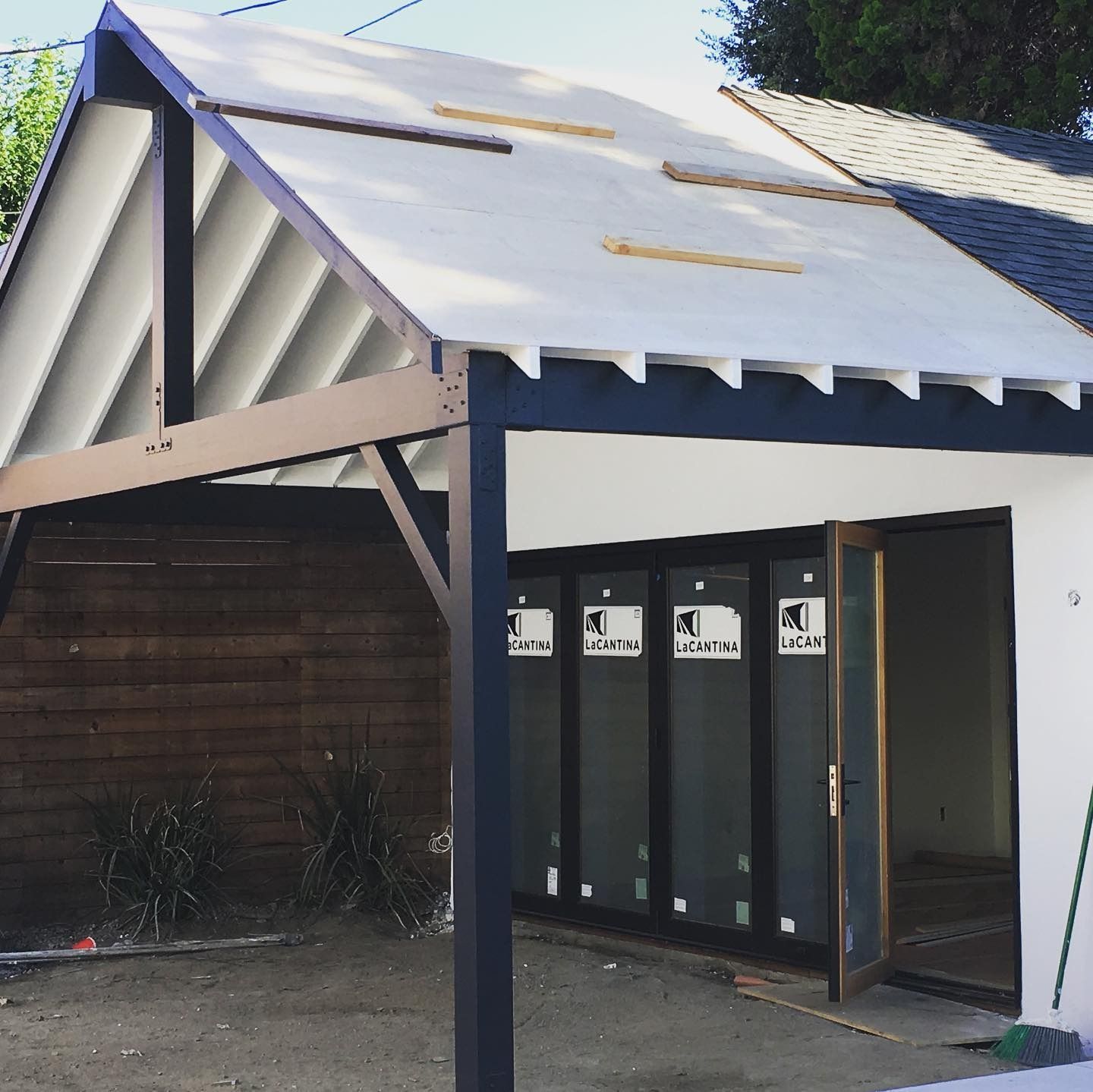 A modern building with a white and dark gray color scheme, featuring a sloped roof and glass doors.