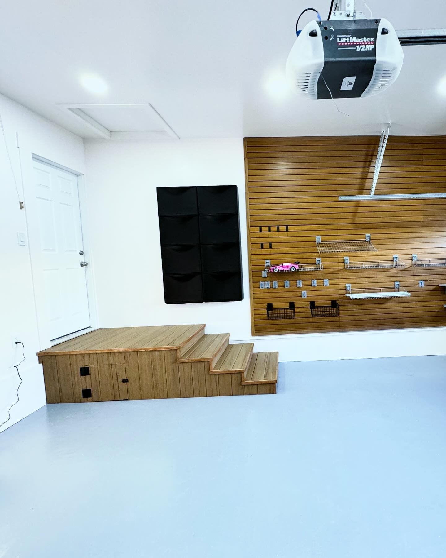 Garage with wooden steps, a black plant wall, and tools displayed on a wood-paneled wall.