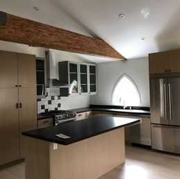 Modern kitchen with stainless steel appliances, island, and arched window.