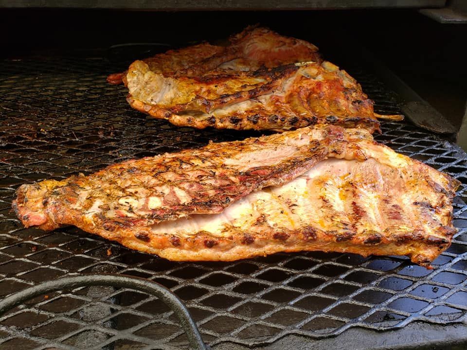 Two pieces of meat are cooking on a grill.