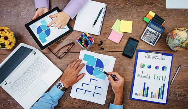 Un gruppo di persone è seduto a un tavolo e guarda grafici e tabelle.