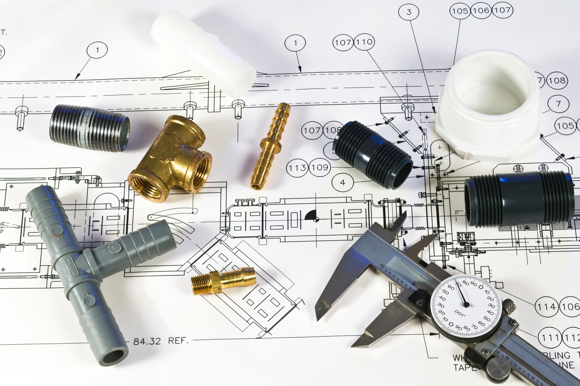 Plumbing fittings and a caliper rest on a technical drawing.